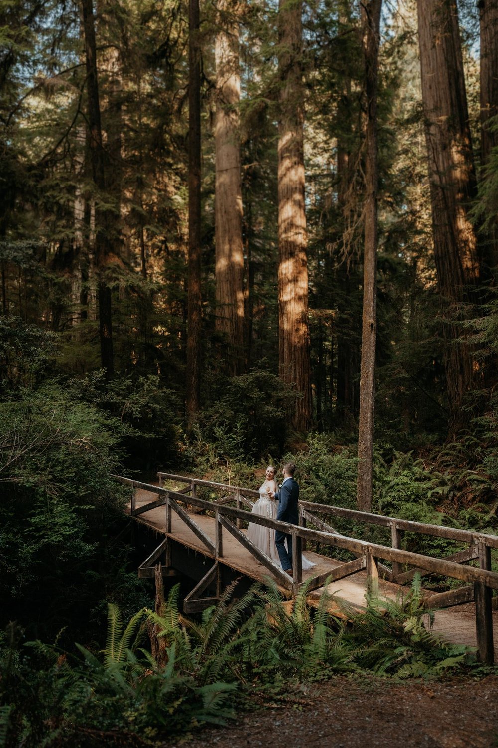 Bride and groom standing on a wood bridge during their forest elopement in California
