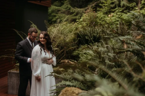 Groom helps bride into her wedding dress while getting ready for their elopement in the North Cascades
