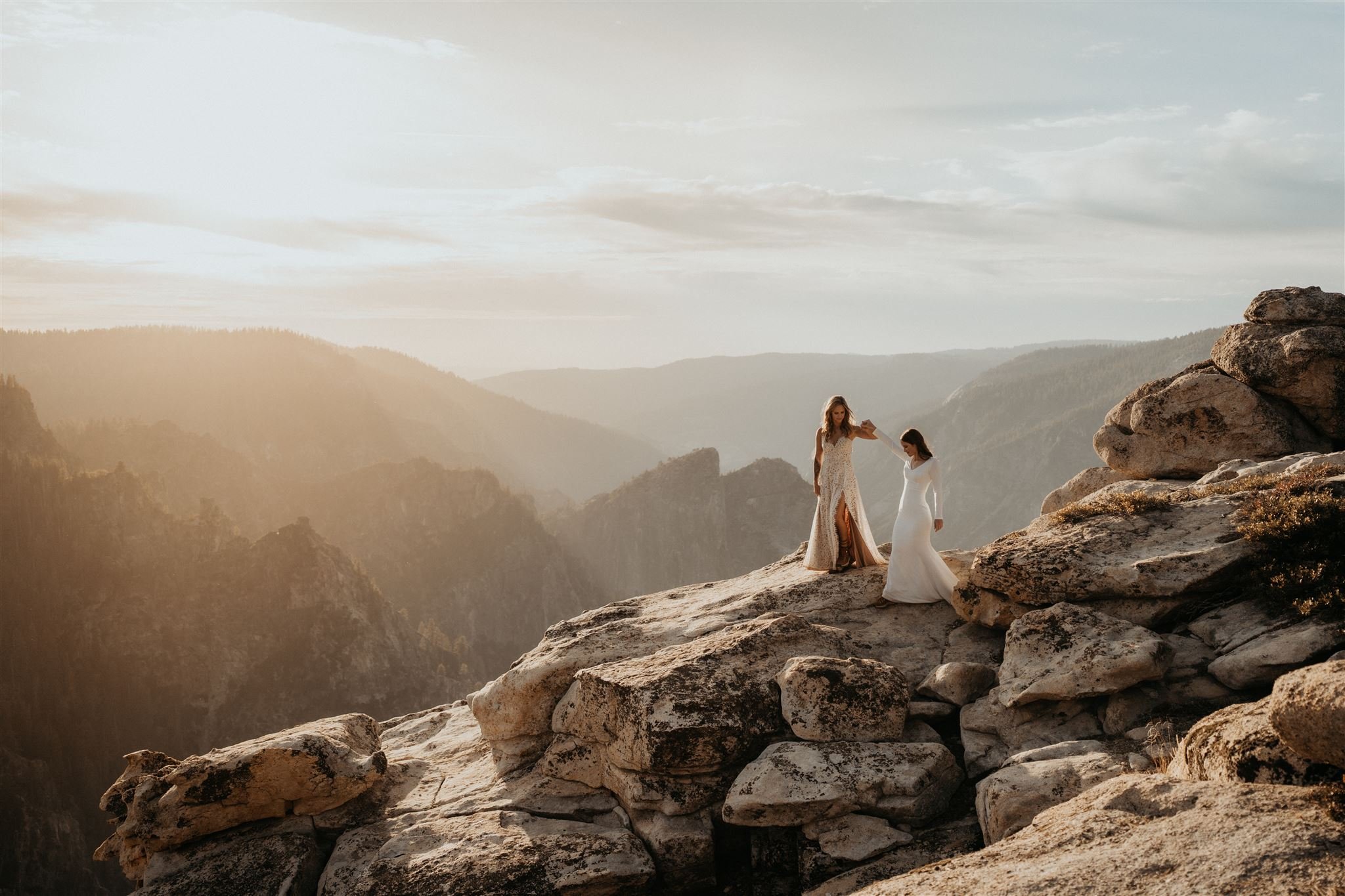 Brides hold hands at their Taft Point elopement in Yosemite