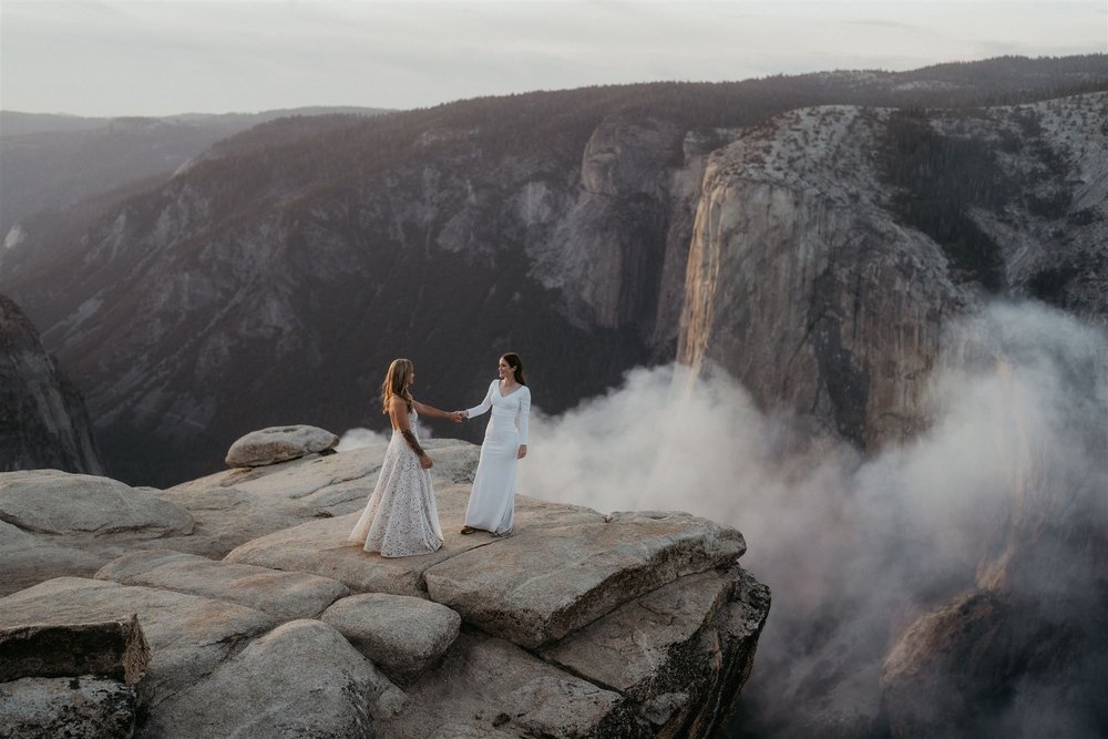 Brides hold hands while walking across Taft Point