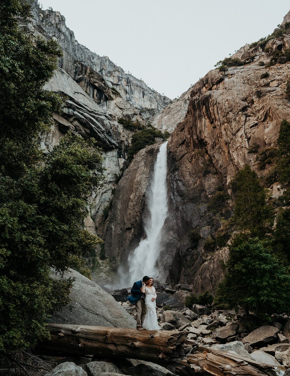 Bride and groom stand under Yosemite Falls at their elopement in Yosemite National Park