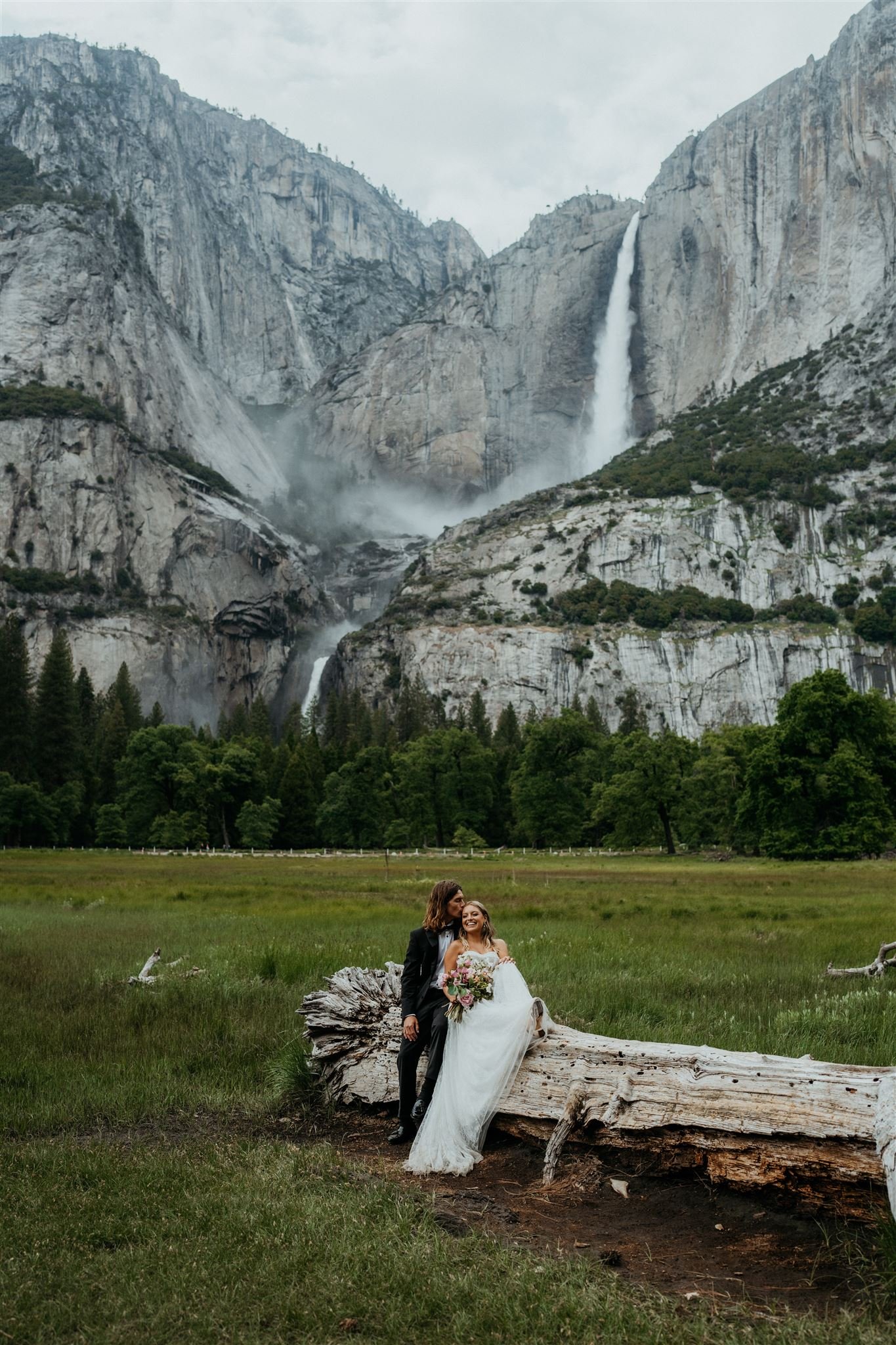 Bride and groom sit on a log at their Yosemite Falls elopement