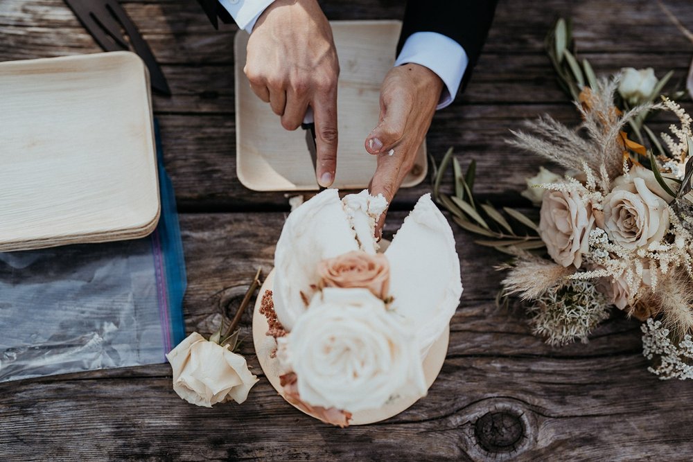 Groom cuts white wedding cake during North Cascades elopement in Washington