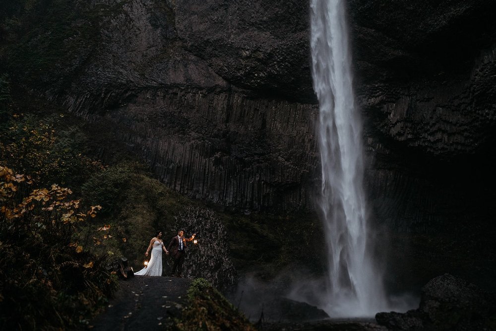 Bride and groom hold lanterns during their waterfall elopement in Oregon