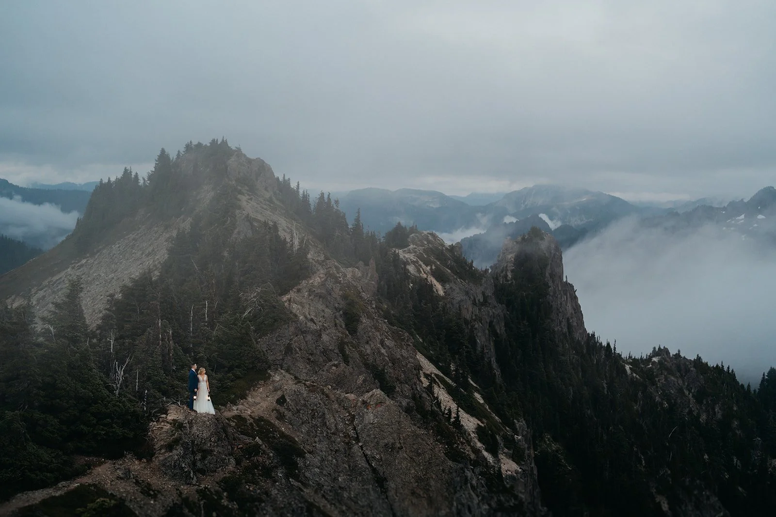 Bride and groom hold lanterns while standing on a mountain trail during their Mount Rainier National Park elopement