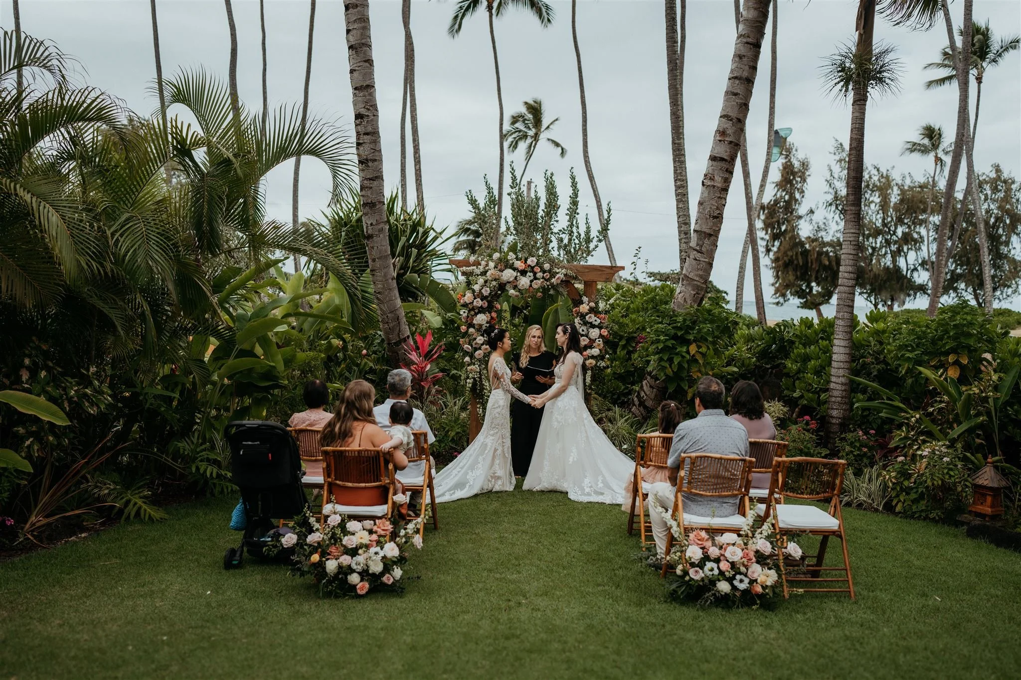 Two brides hold hands during their intimate wedding ceremony in Oahu