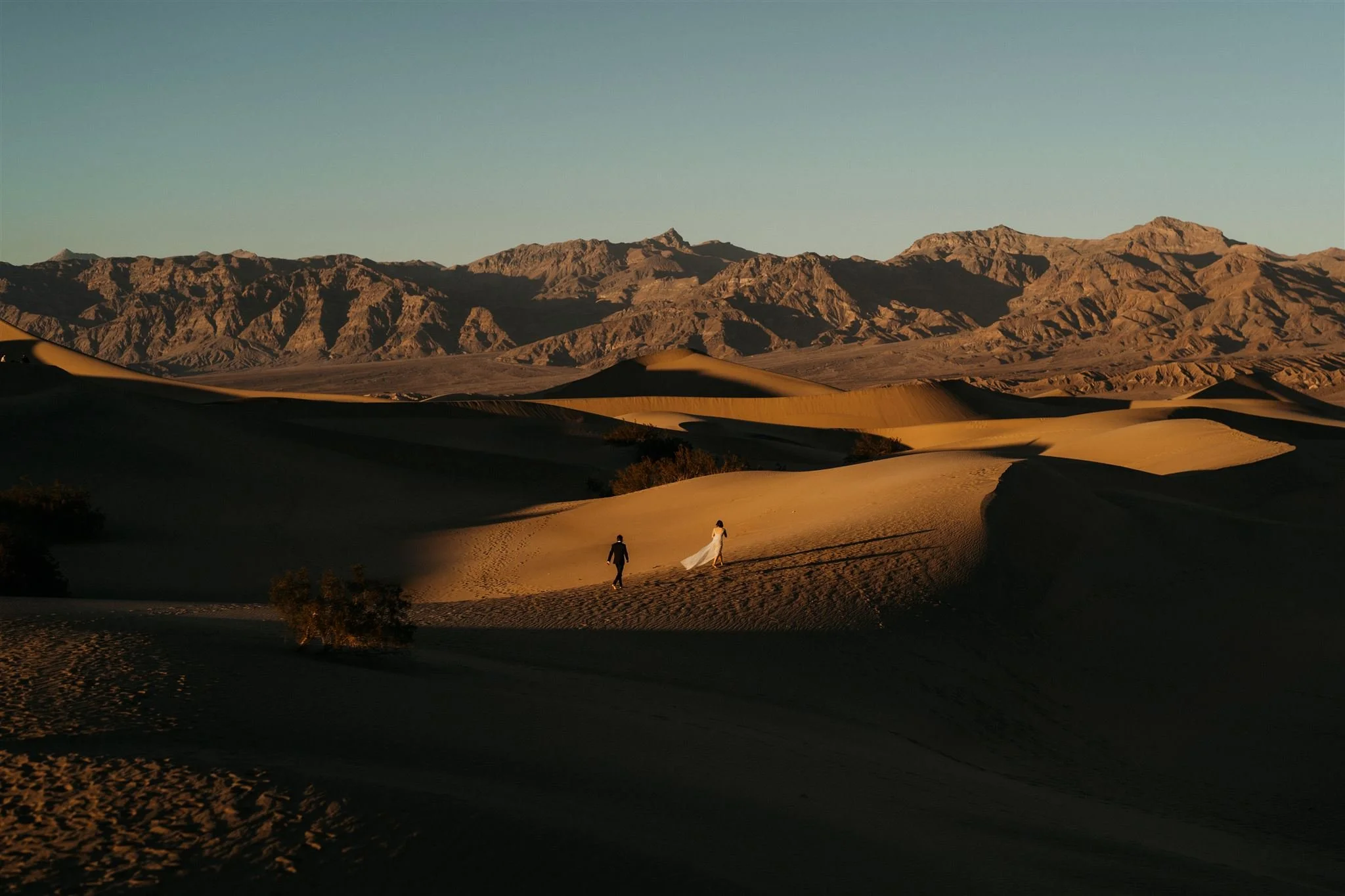 Bride and groom running through the sand dunes at their Death Valley National Park elopement