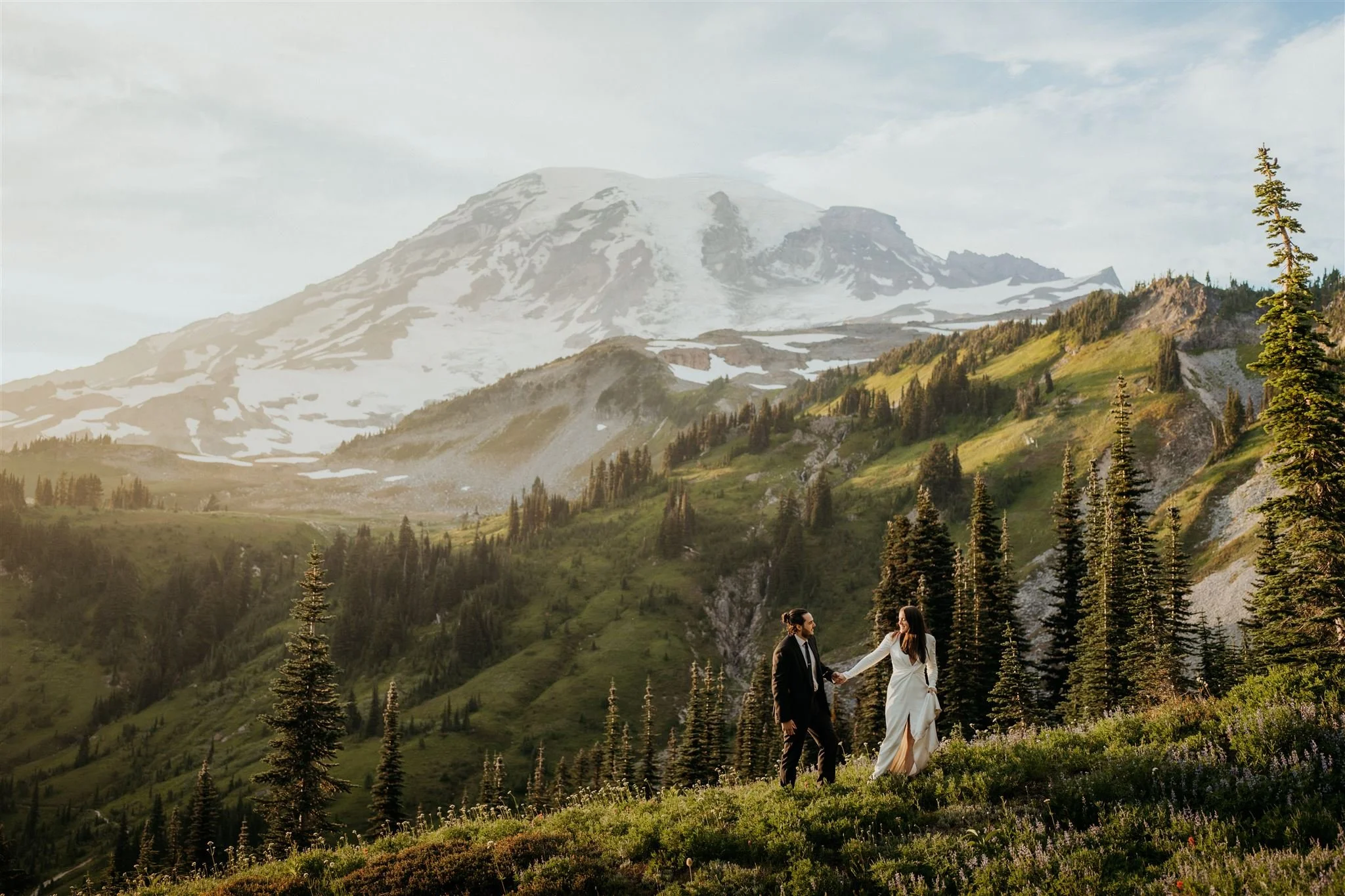 Bride and groom holding hands while walking through Mount Rainier National Park for their elopement