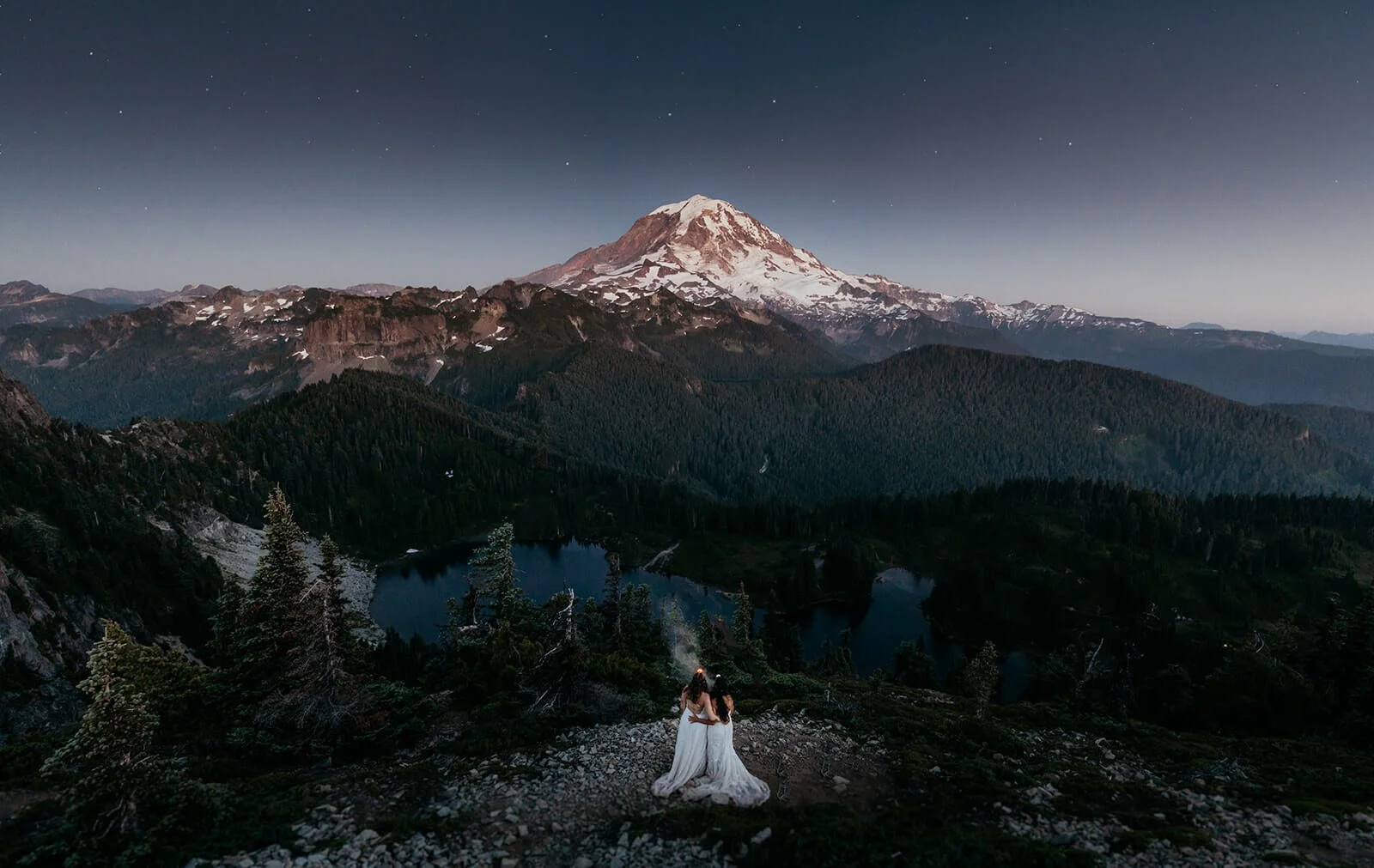 Two brides looking out at Mt Rainier during their hiking elopement