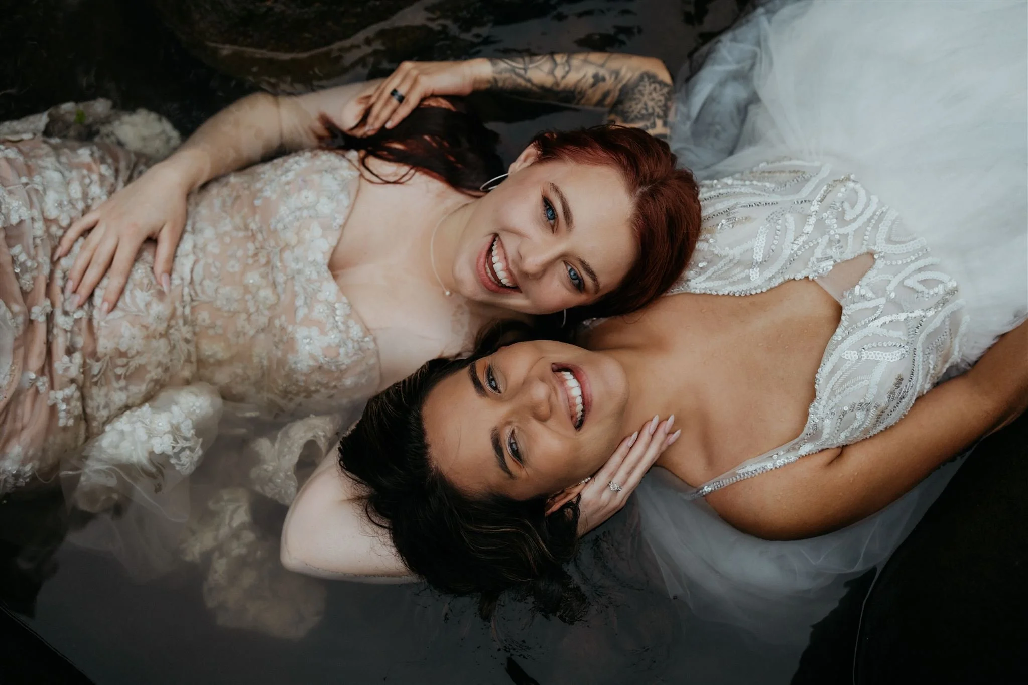 Elopement Photographer photos of two brides laying in the water