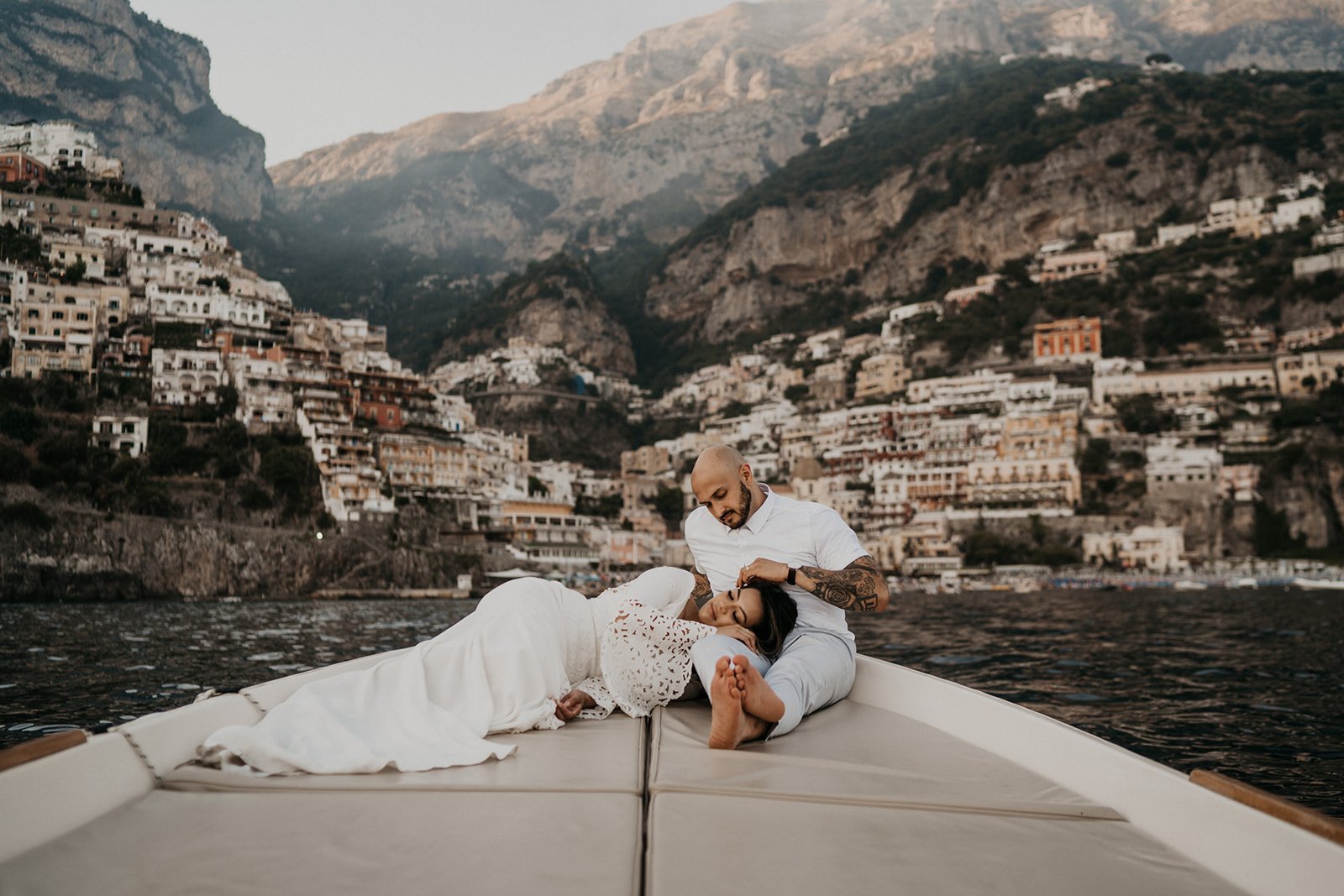Bride and groom sitting on a boat with Positano views in the background