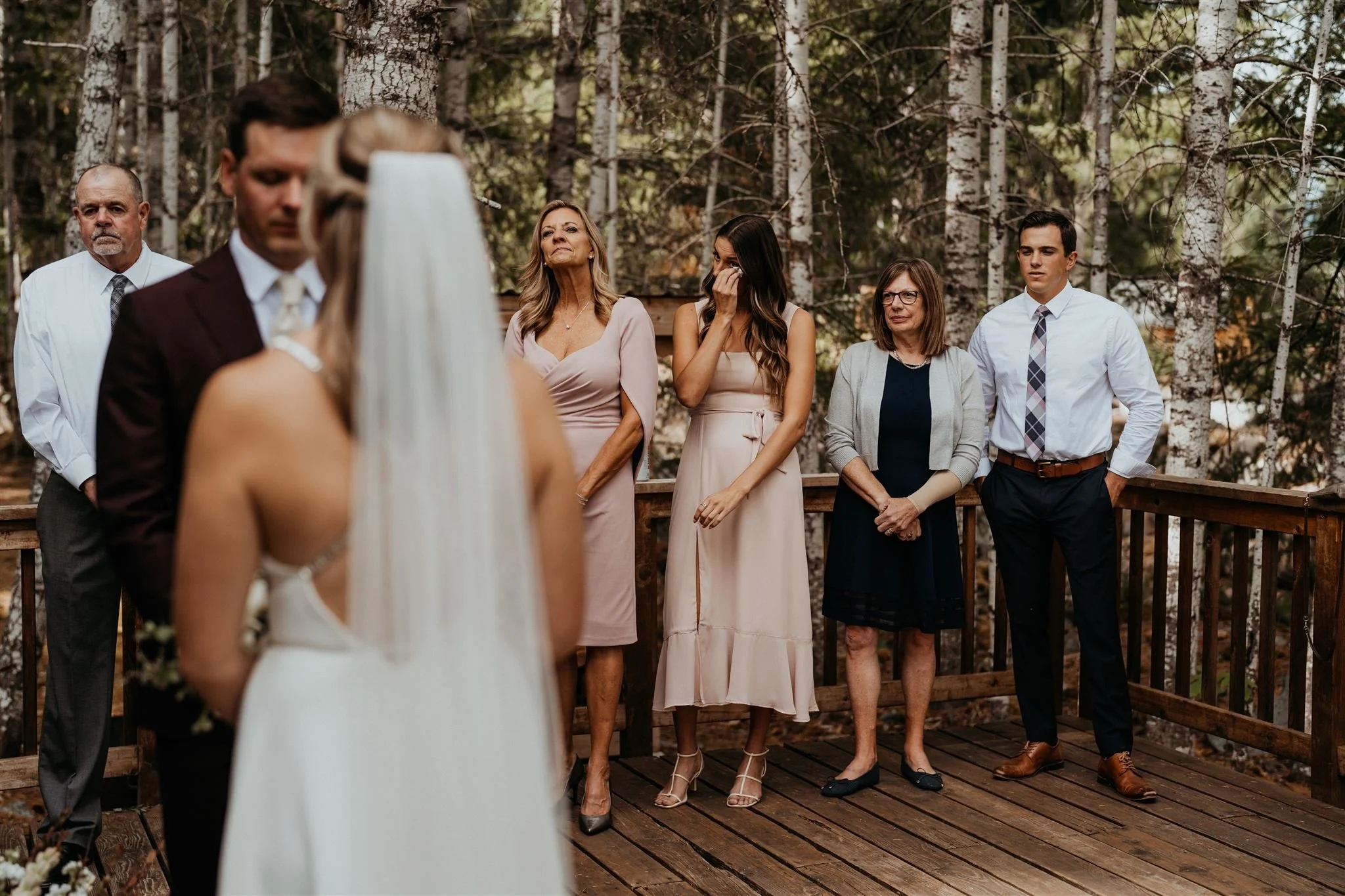Wedding guests watching bride and groom exchange vows at their A-frame cabin elopement