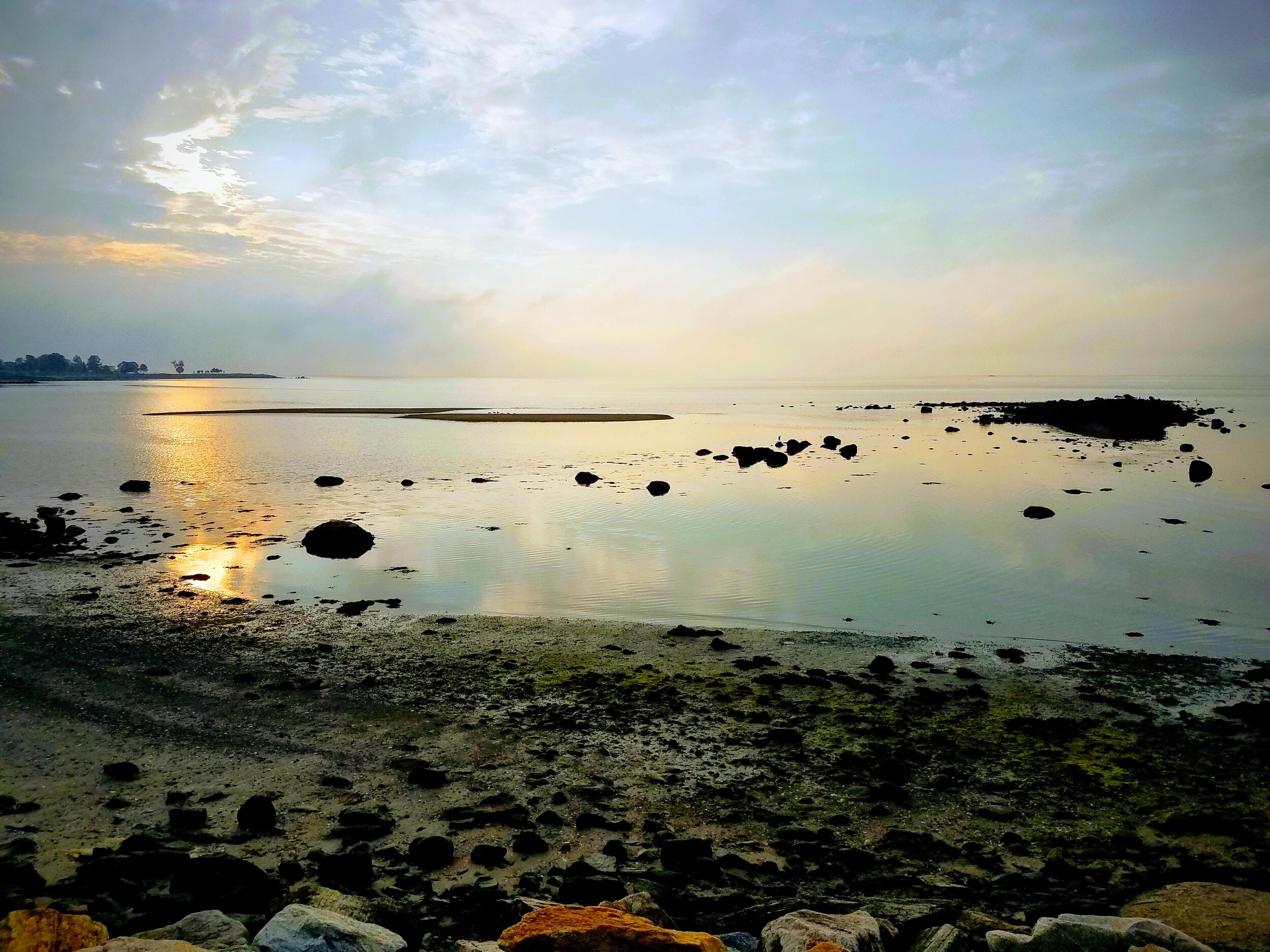 Tranquil seascape at sunset with rocks and shallow water