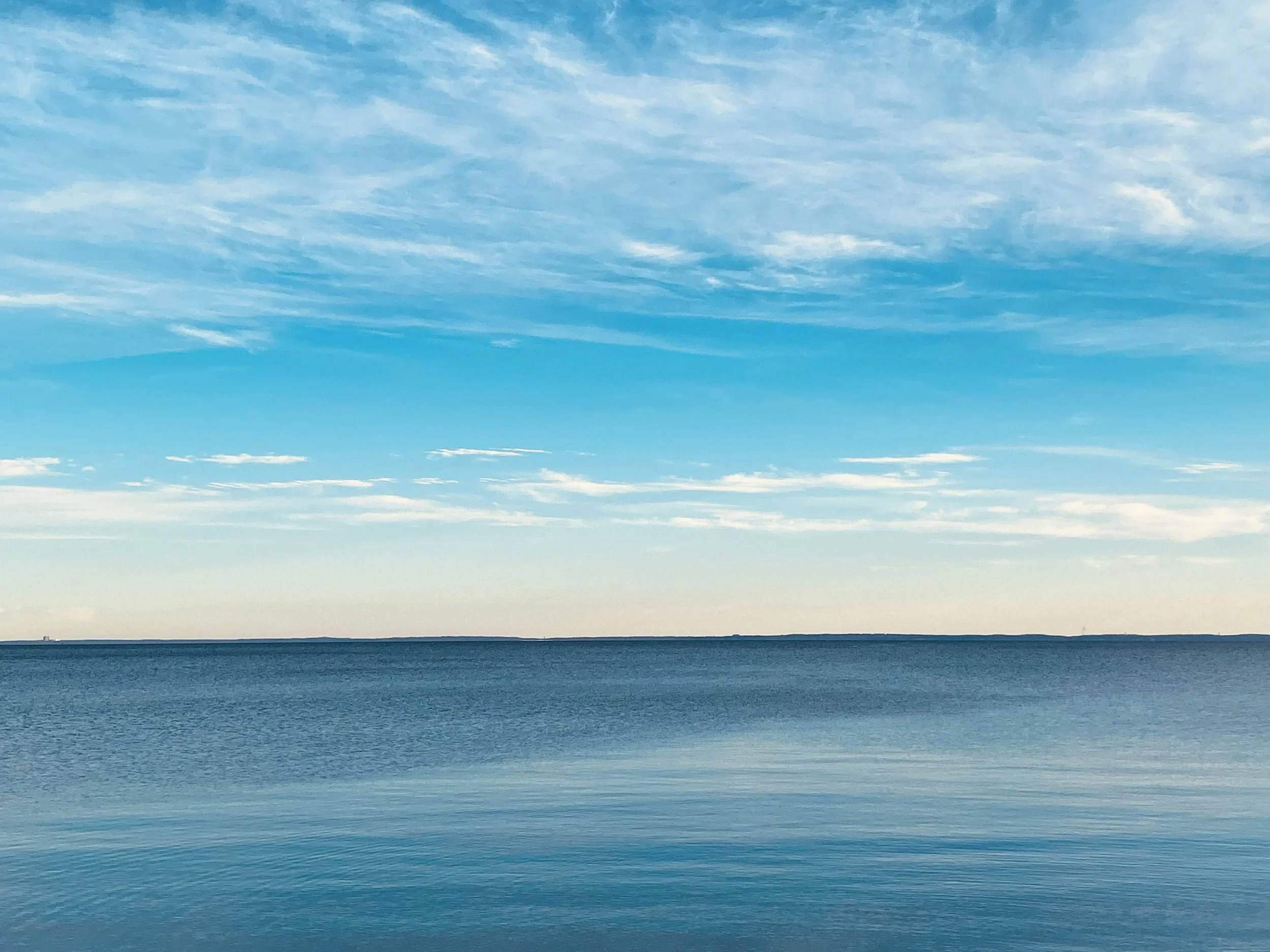 Calm blue sea under a clear sky with light clouds