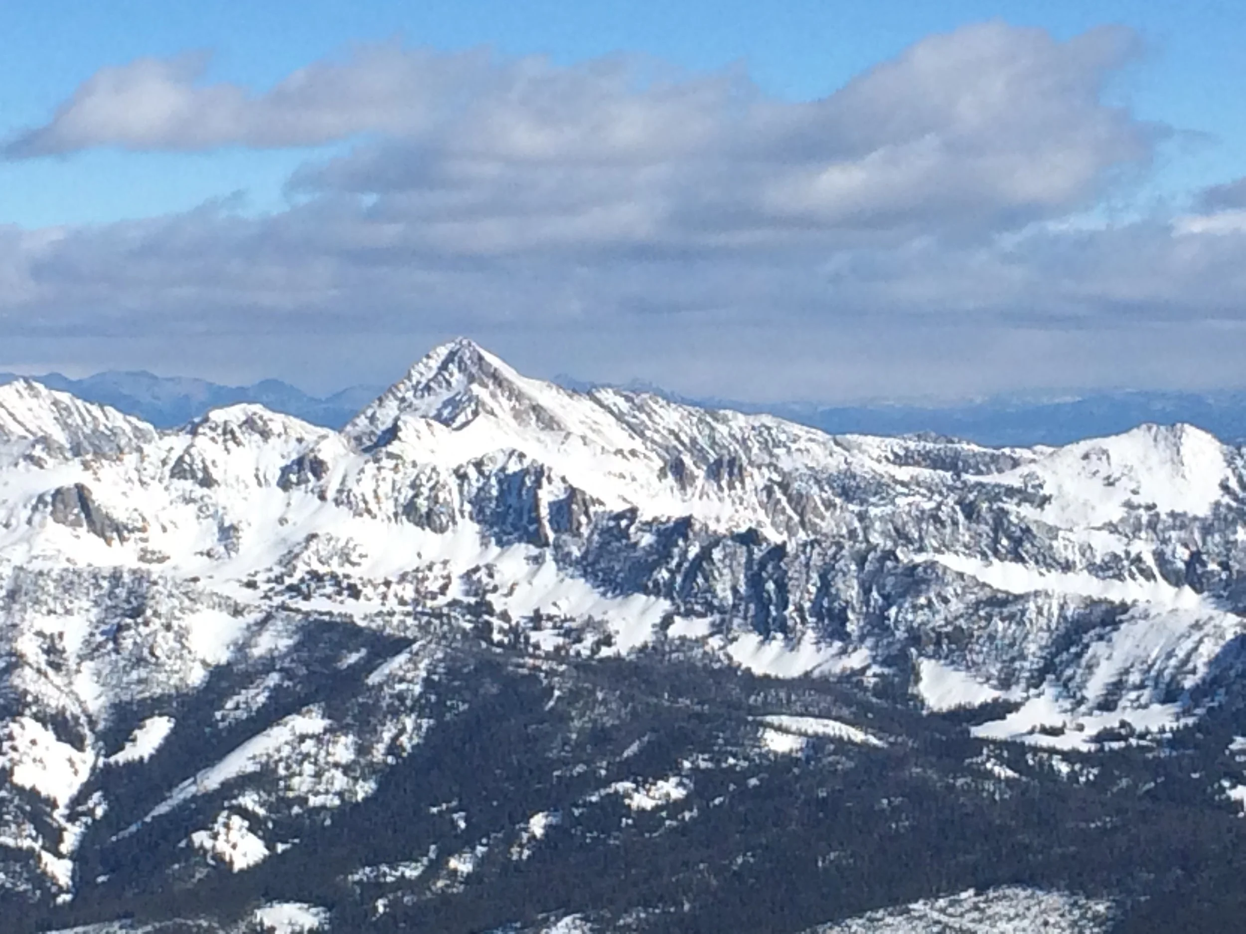 Snow-covered mountain range under cloudy sky