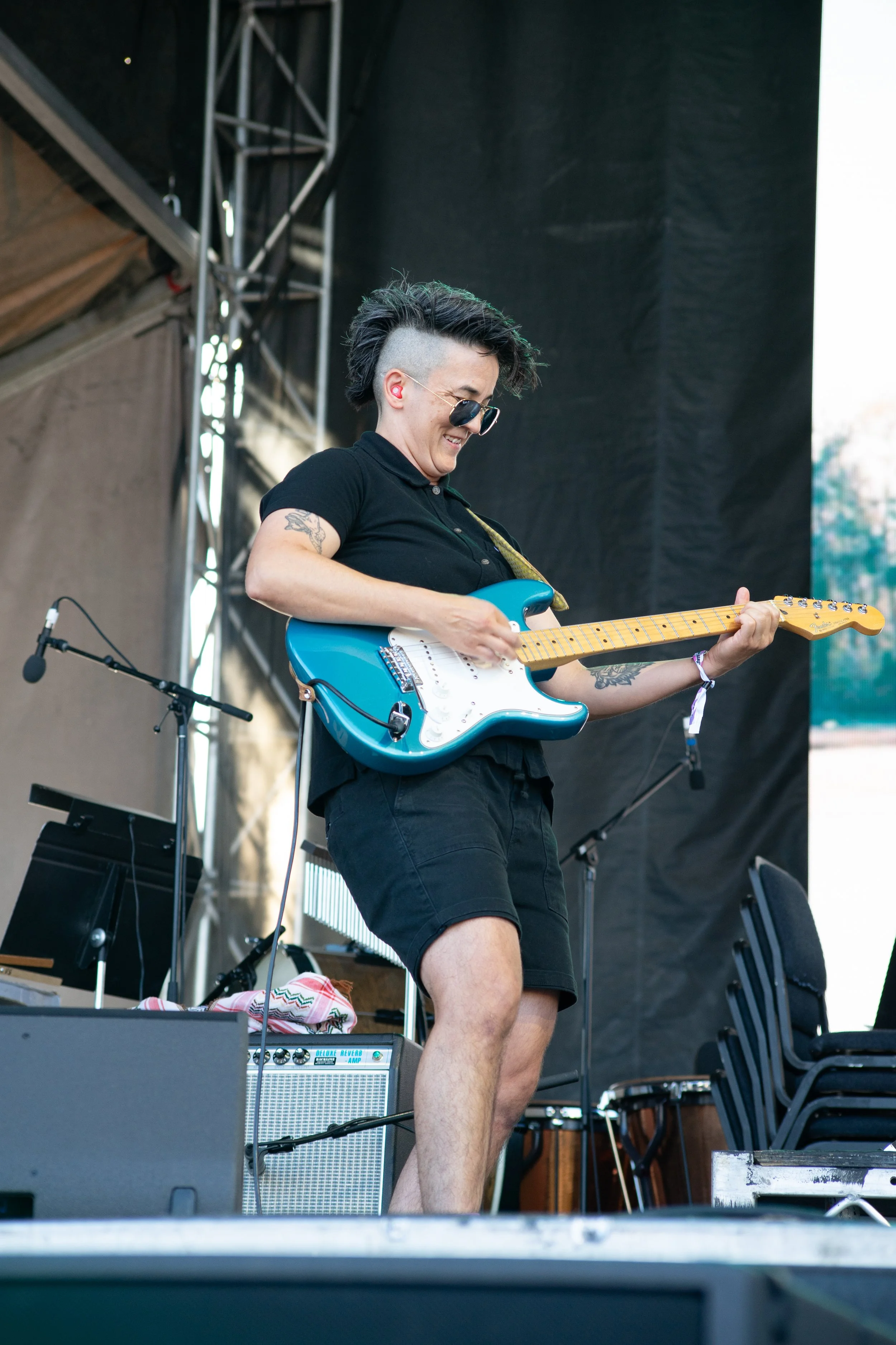 Dana Okinawa playing a blue guitar on stage.