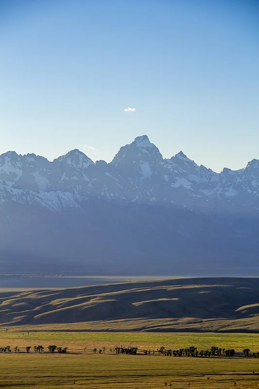 The Grand Tetons during sunset as the sun is behind the mountains.