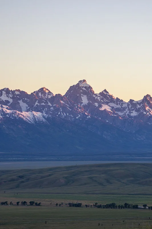 The Grand Tetons during sunrise as the sun is hitting the mountains.