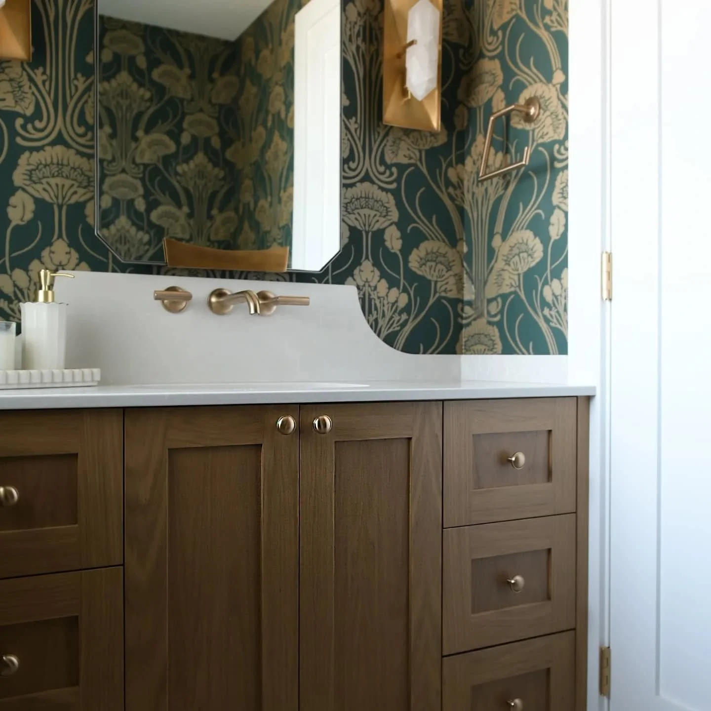 ✨ Classic meets bold in this stunning West Vancouver powder room! The rich, warm wood tones of the cabinetry perfectly complement the statement-making floral wallpaper and the elegant gold and white fixtures. Every detail from the sleek faucets to th