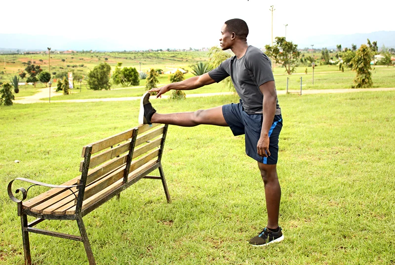 Young-Man-Stretching-Legs-on-A-Bench-in-the-Park-Before-Running.jpg