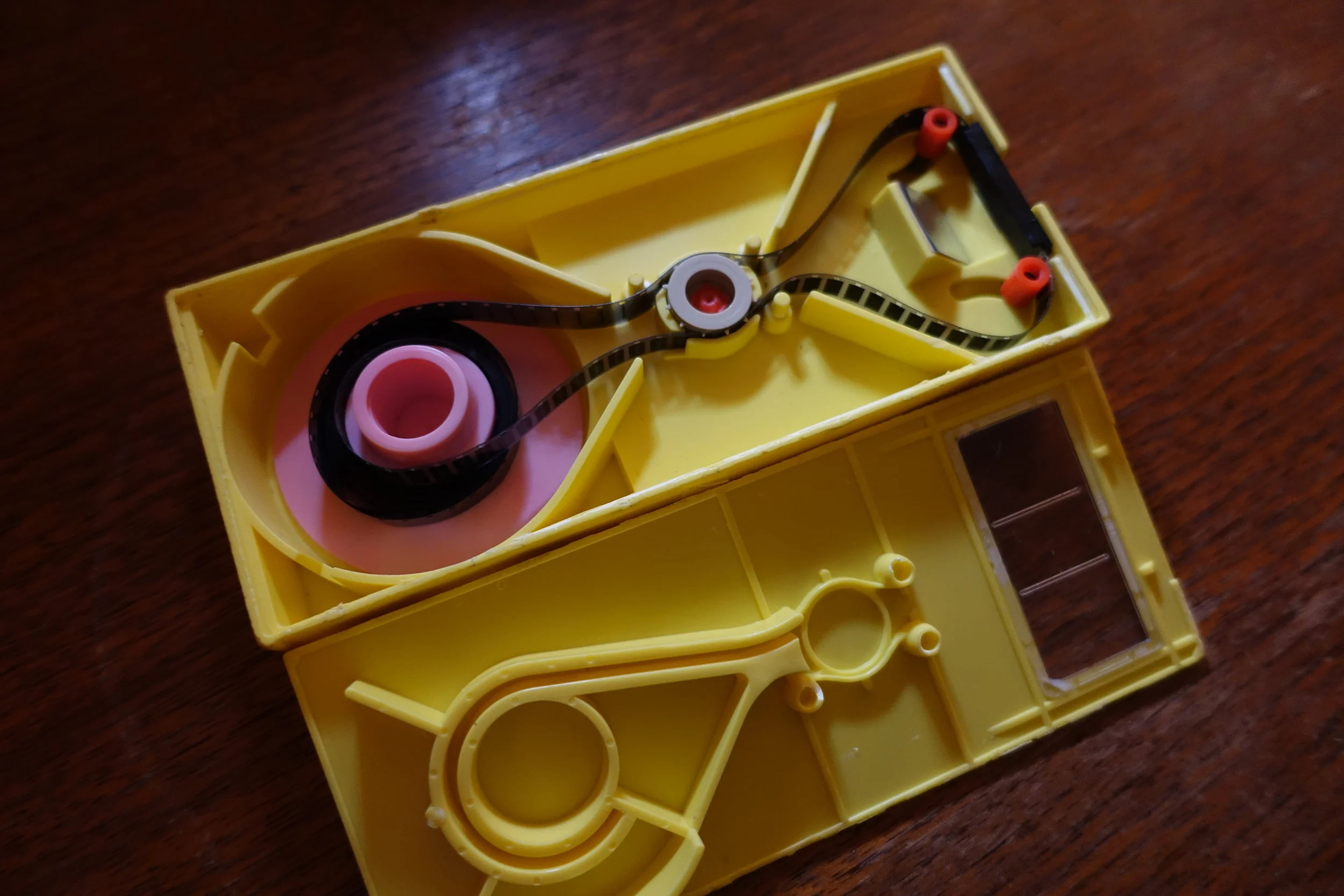  Interior of the cartridge showing the coaxial mechanism and new film installed. The cartridges feature a built in mirror to reflect the projected image. The image is focused through a pair of condenser lenses before hitting 2 more mirrors directing 