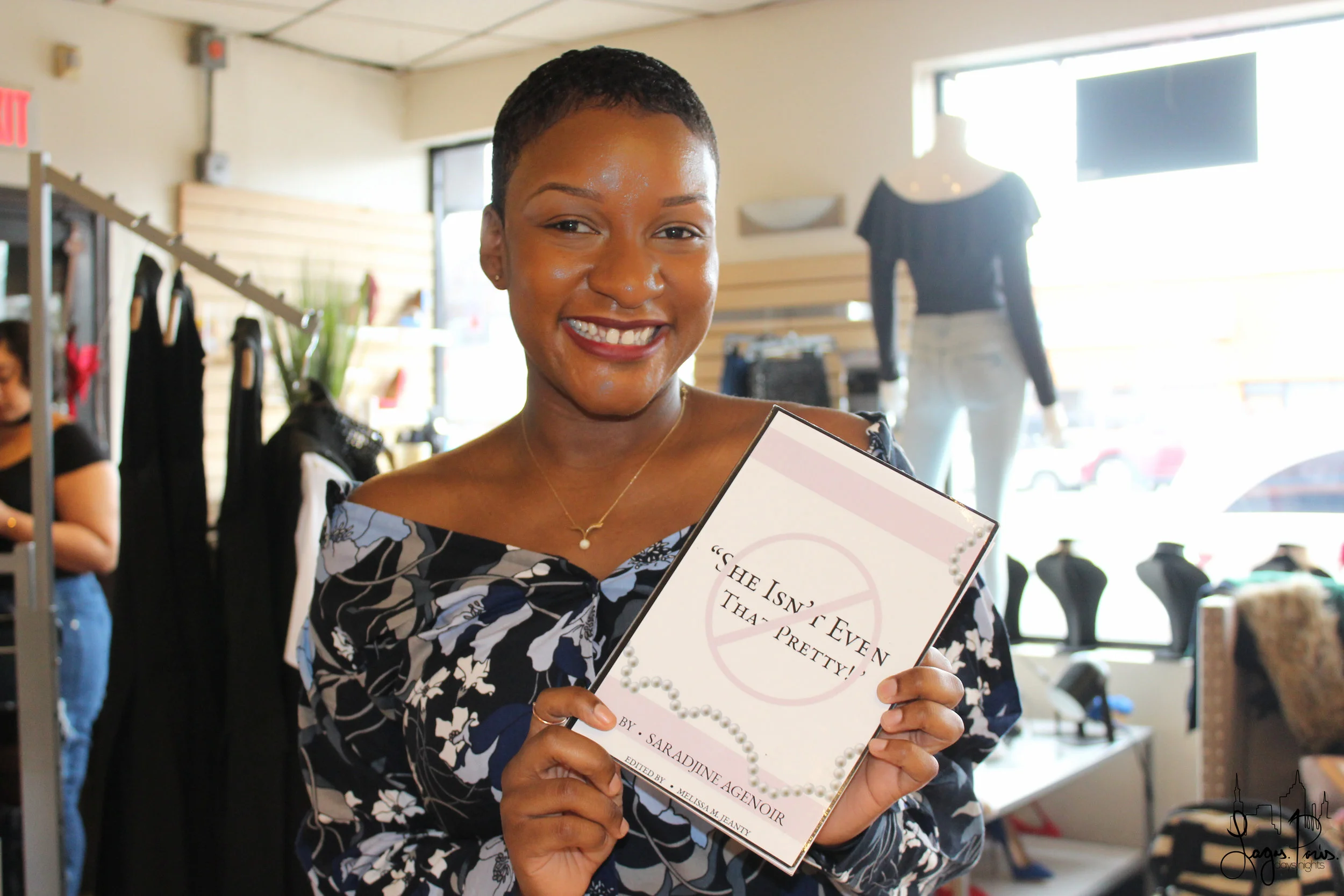 Saradjine poses for the camera while holding a copy of her book She Isn't Even That Pretty .