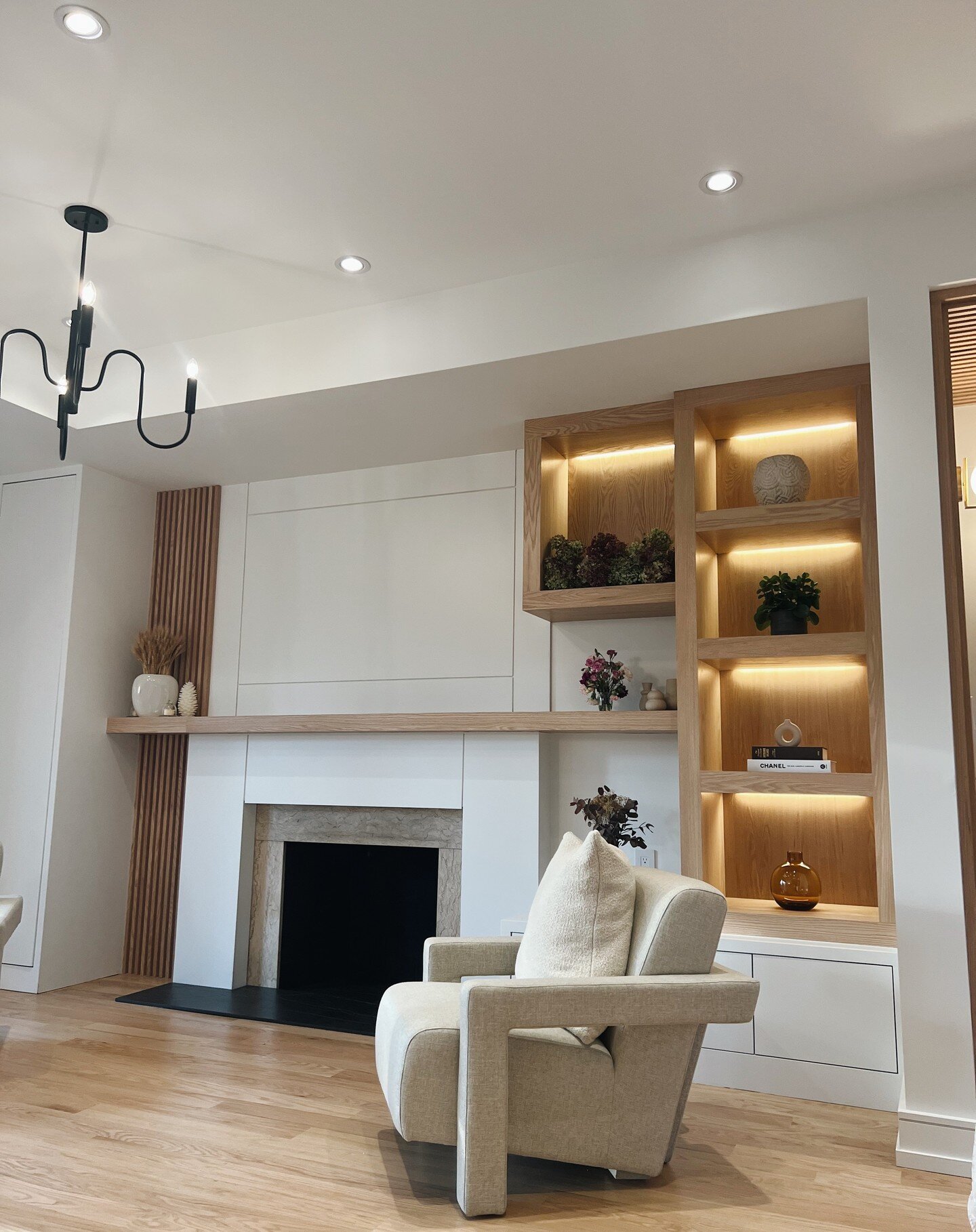 In this custom home renovation, we were commissioned to cover the entire main floor with customized builds. This triple-wall unit build seamlessly integrates the same design tone, showcasing oak slat contrast and 1/4 by 1/4 grooved MDF paneling. It i