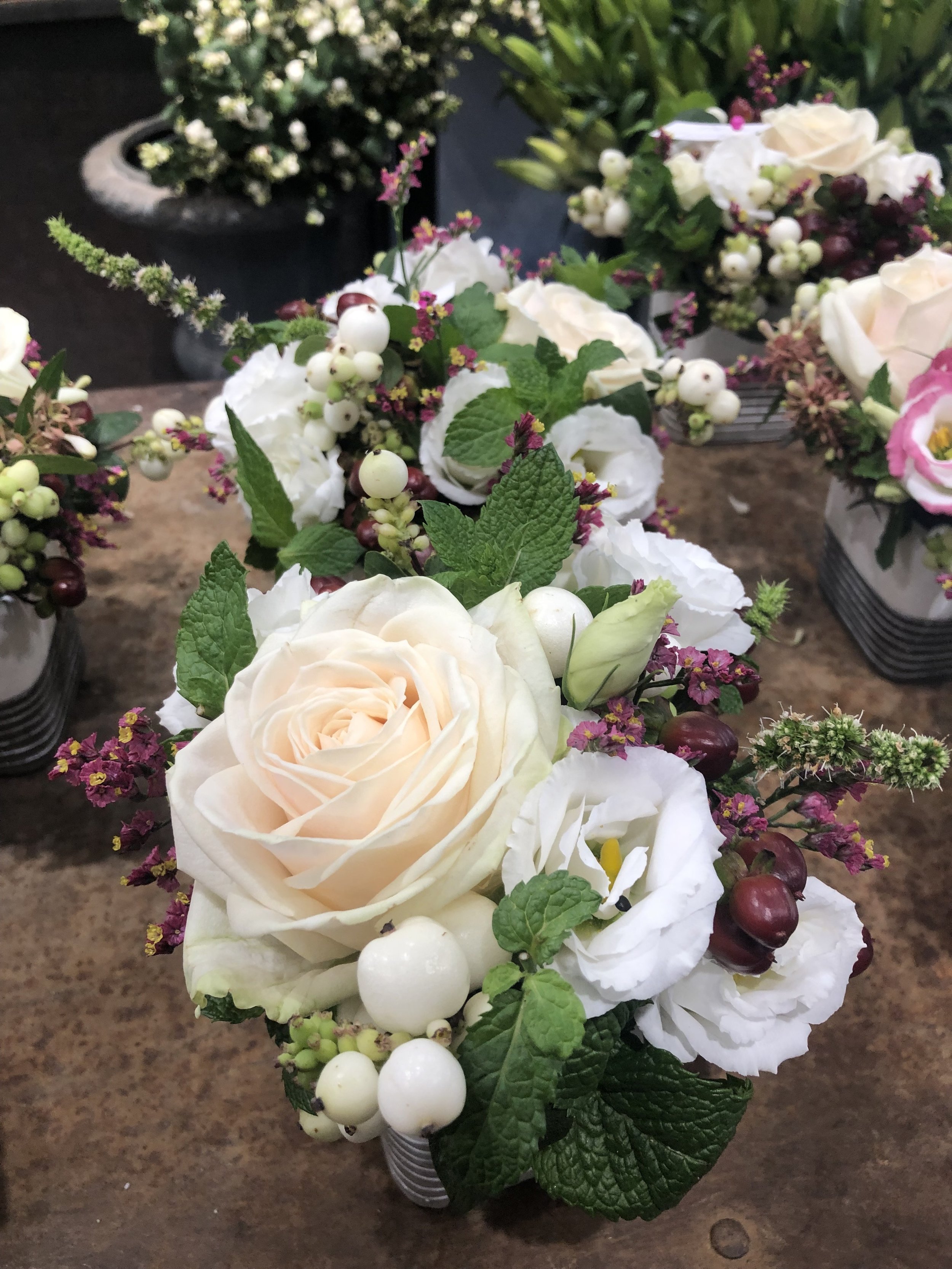 Miniature nosegay arrangements with garden roses, lisianthus, snowberry, mint