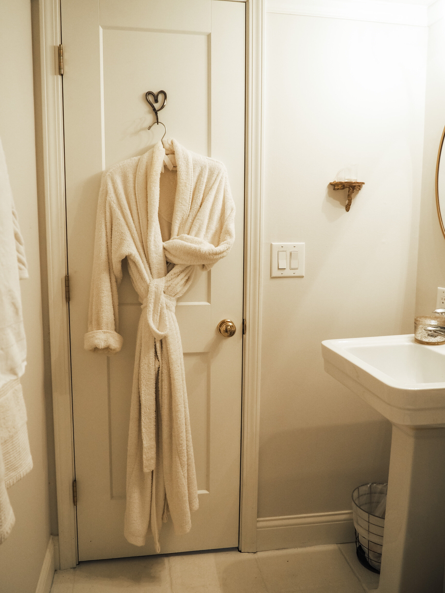 A white terrycloth robe hangs on a hand-forged iron heart hook the back of the door.