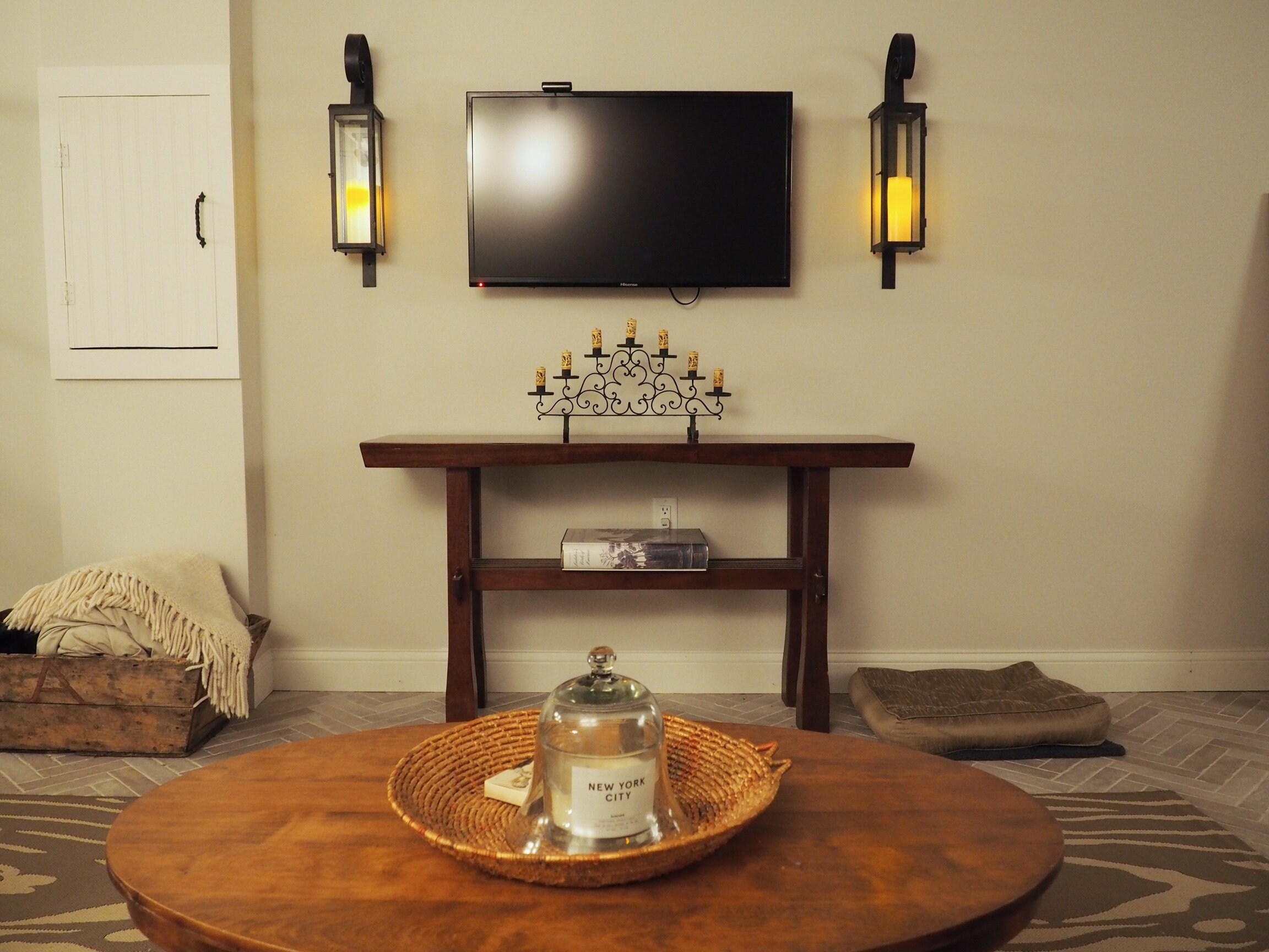 Iron candle sconces add warmth and interest to the TV wall; the console table holds a wrought iron candelabra with wine cork candles.