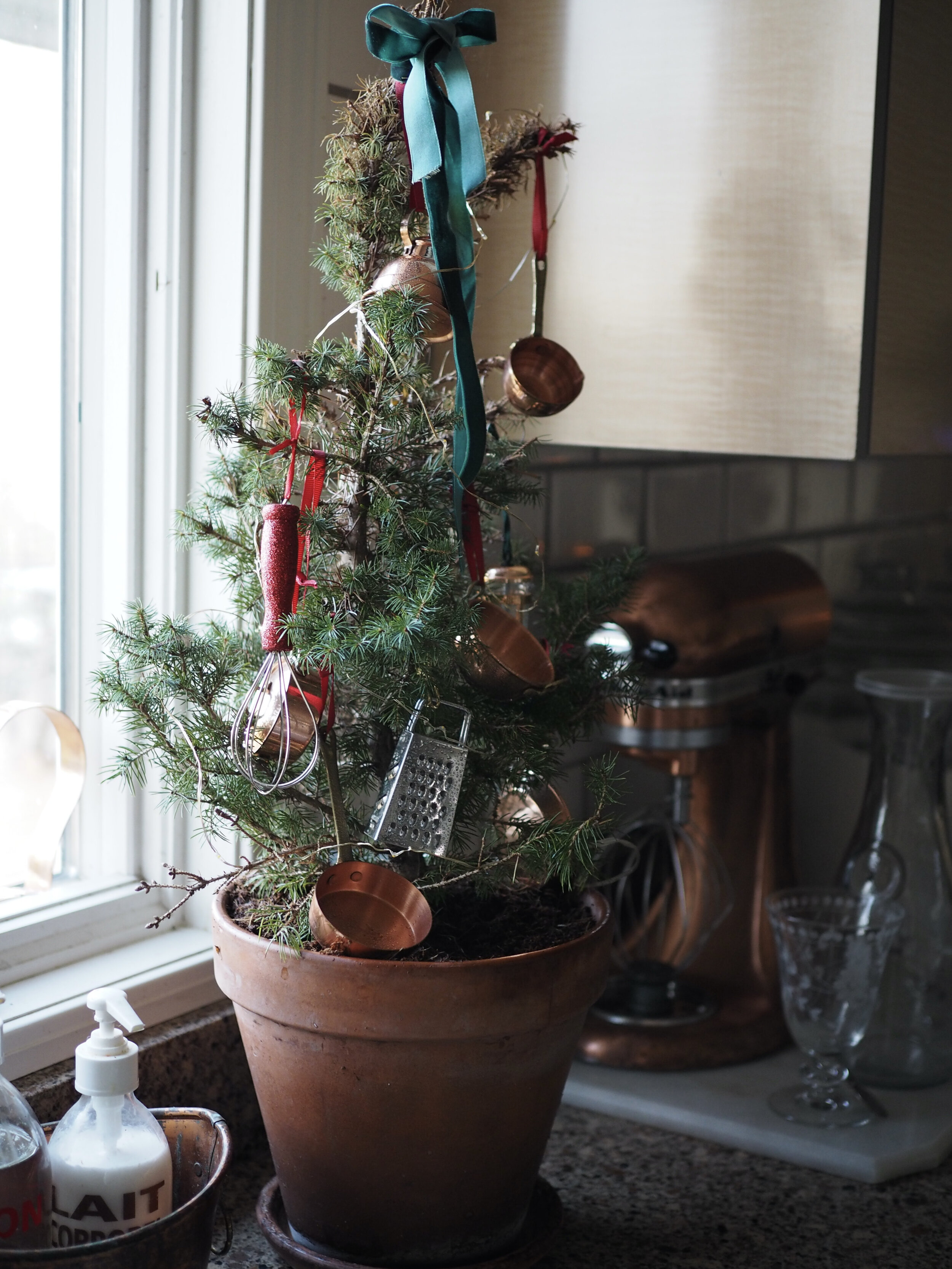 A mini potted Alberta spruce is dressed up with my collection of mini copper cookware in the kitchen
