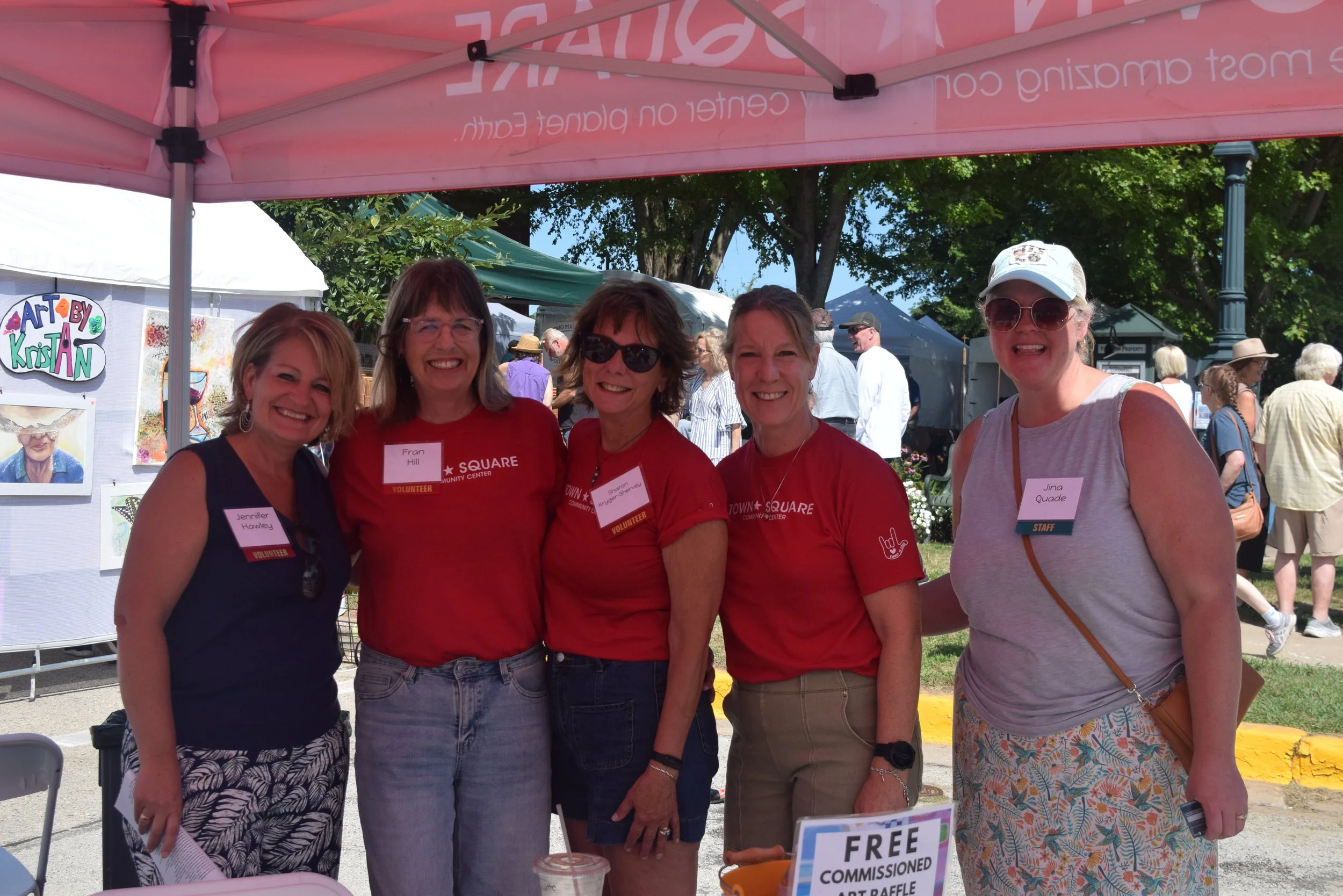Town Square staff and volunteers gather for a group photo beneath a tent at the Green Lake Fine Art Show.
