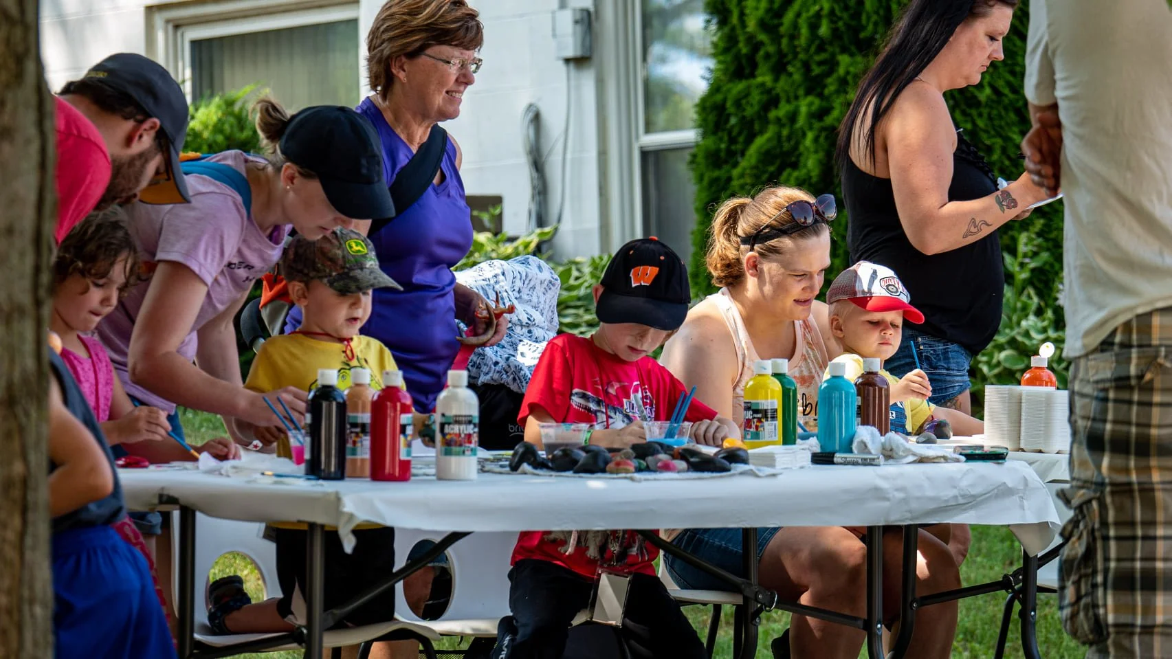 Children and families paint rocks together at an outdoor art station during Dino Daze.