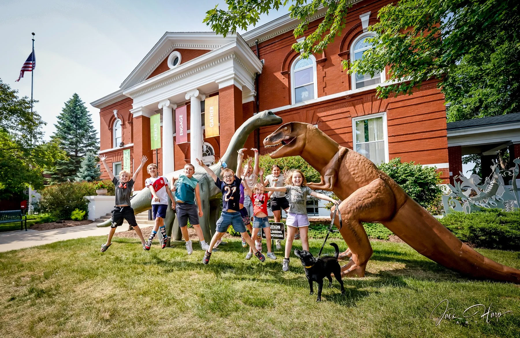 Children jump in front of large dinosaur displays outside Town Square during Dino Daze.