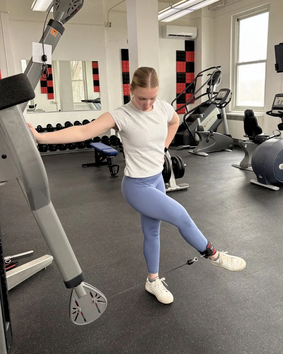 Gym member using cable machine for leg raise.