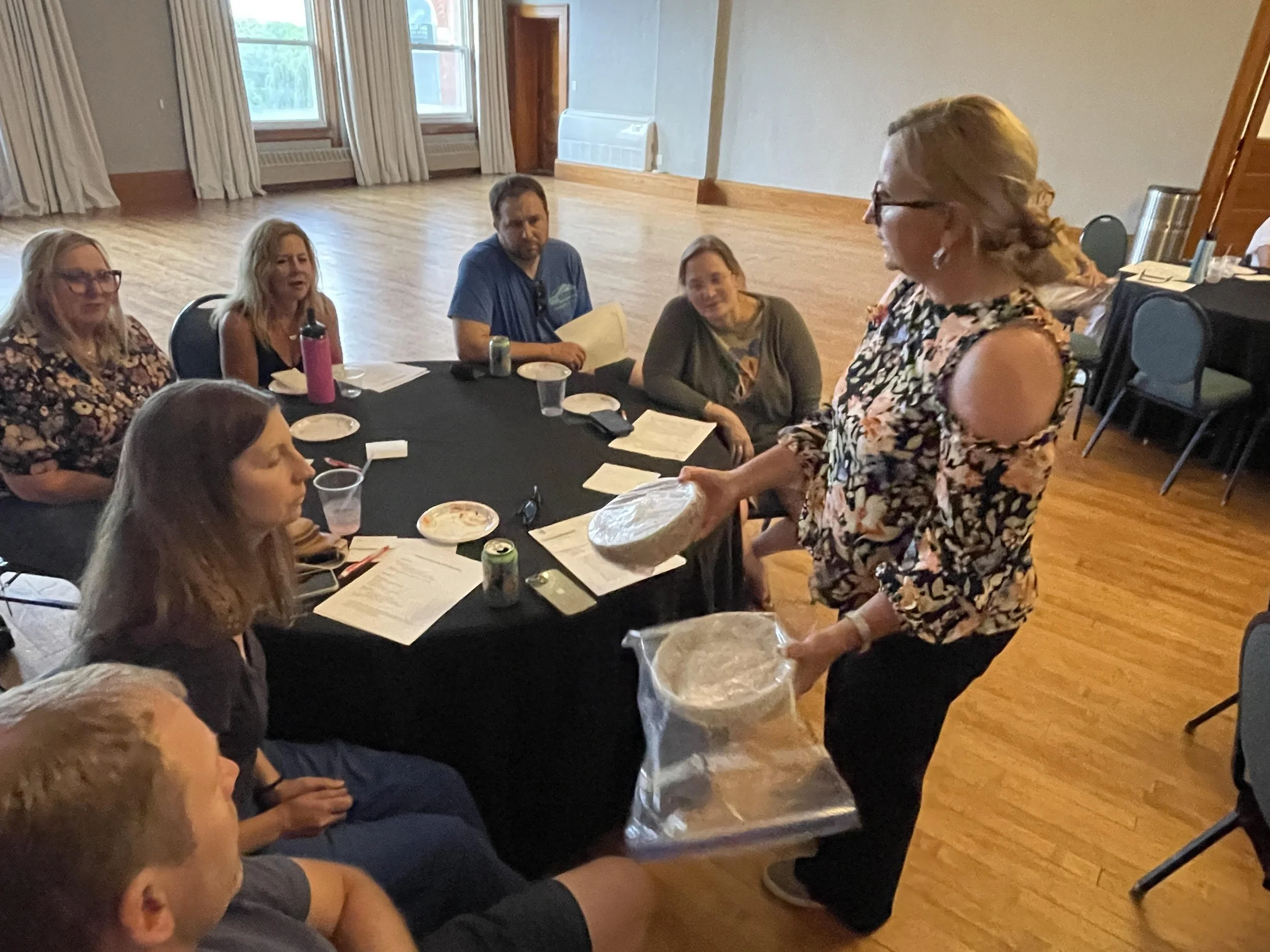 A presenter shares materials with participants seated around a table during a community workshop at Town Square.