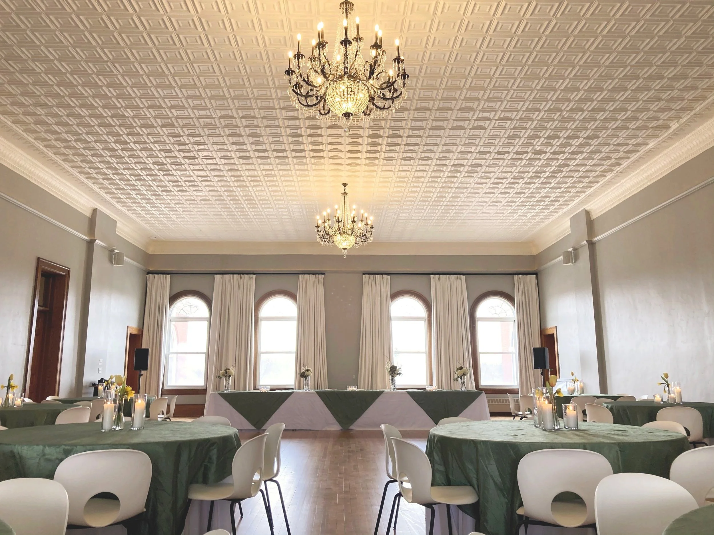 Historic Ballroom at Town Square Community Center set up for an event with round tables beneath chandeliers and a decorative ceiling.