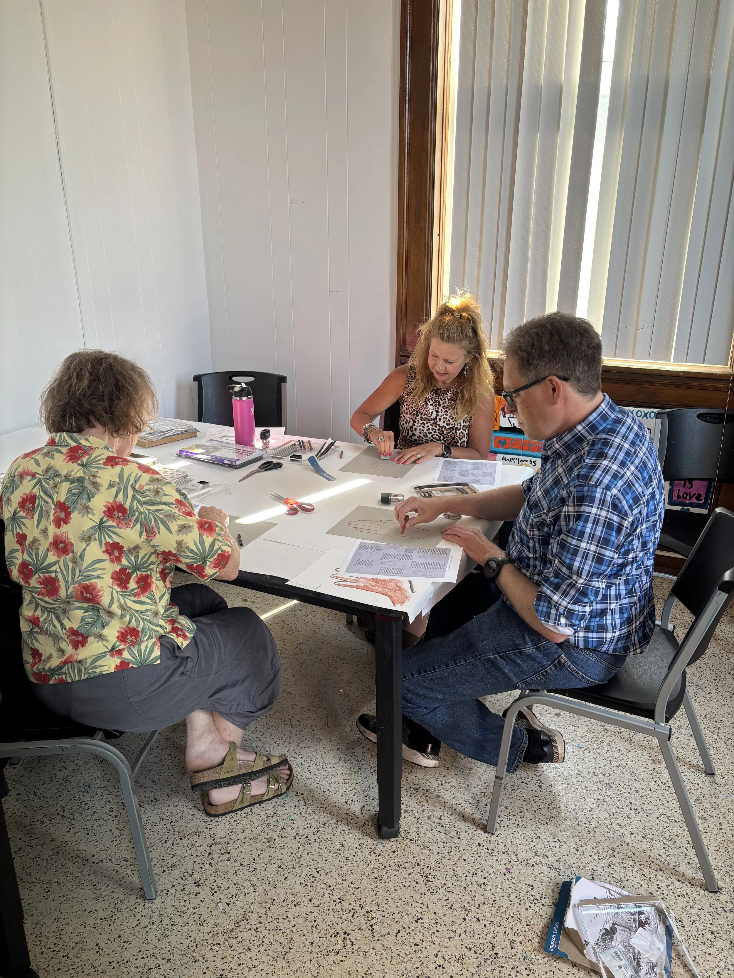 Three adults work on drawing projects during an art class in the MakerSpace at Town Square Community Center.