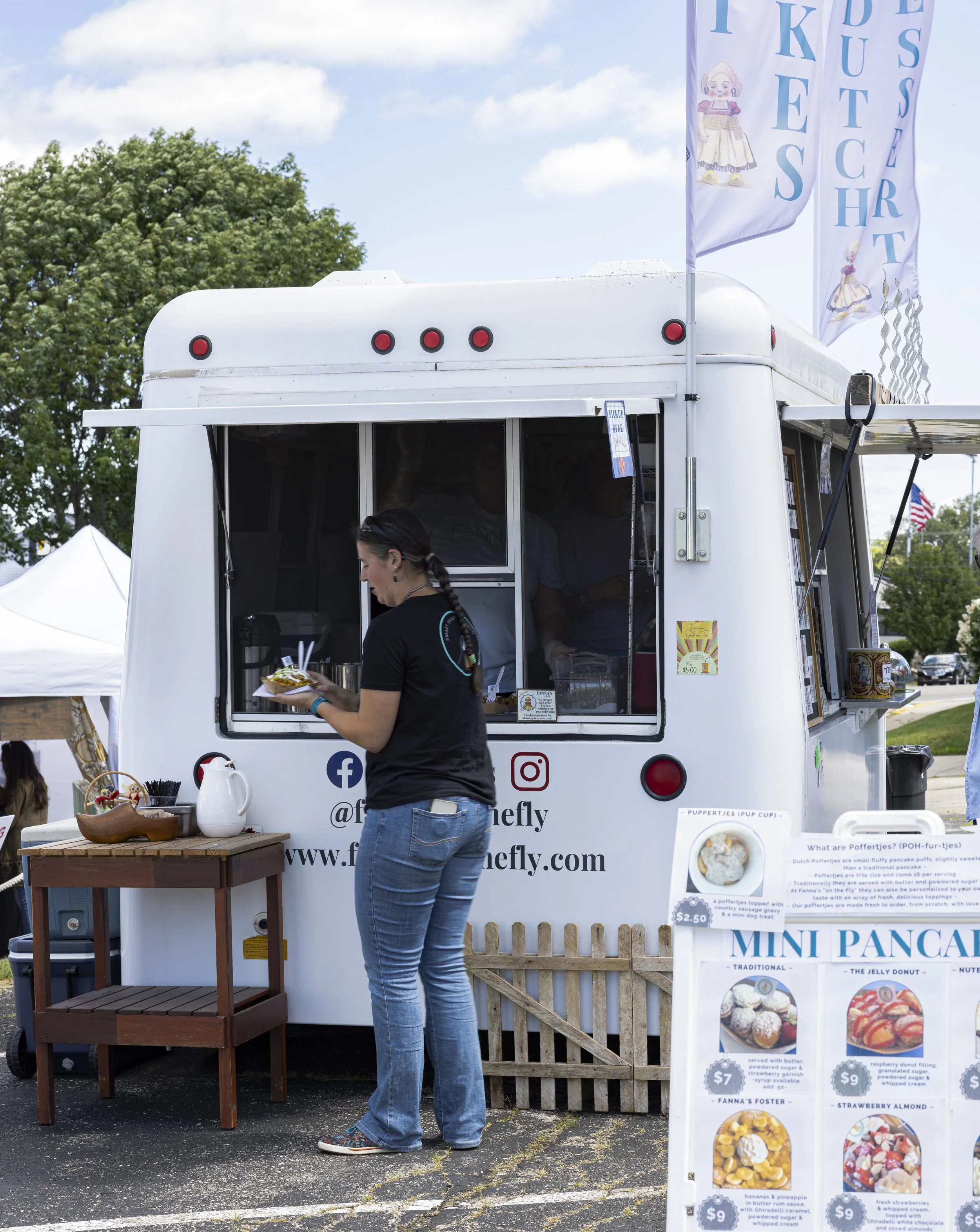 A local food vendor serves festival guests during the Green Lake Fine Art Show, where delicious food, live entertainment, community gathering spaces, and fine art create a memorable visitor experience.