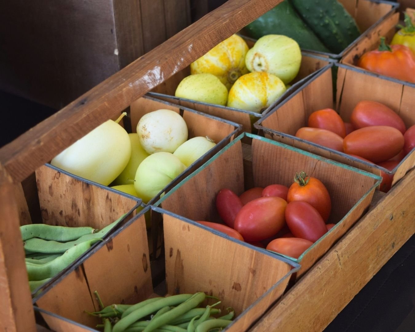 Fresh tomatoes, beans, cucumbers and other locally grown produce displayed in baskets at the Town Square Summer Market.