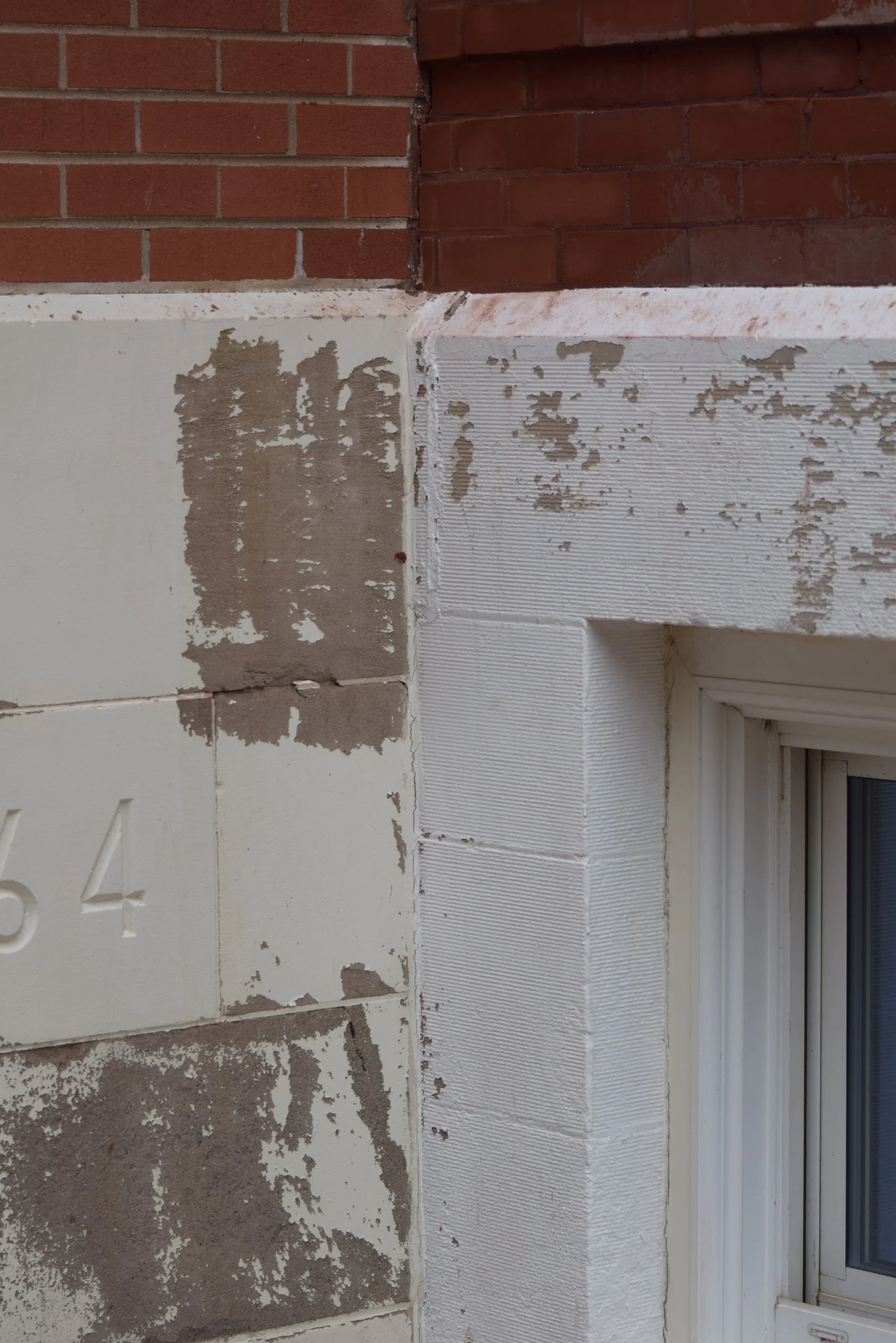 Peeling paint and weathered masonry around a window on the exterior of the historic Town Square building.