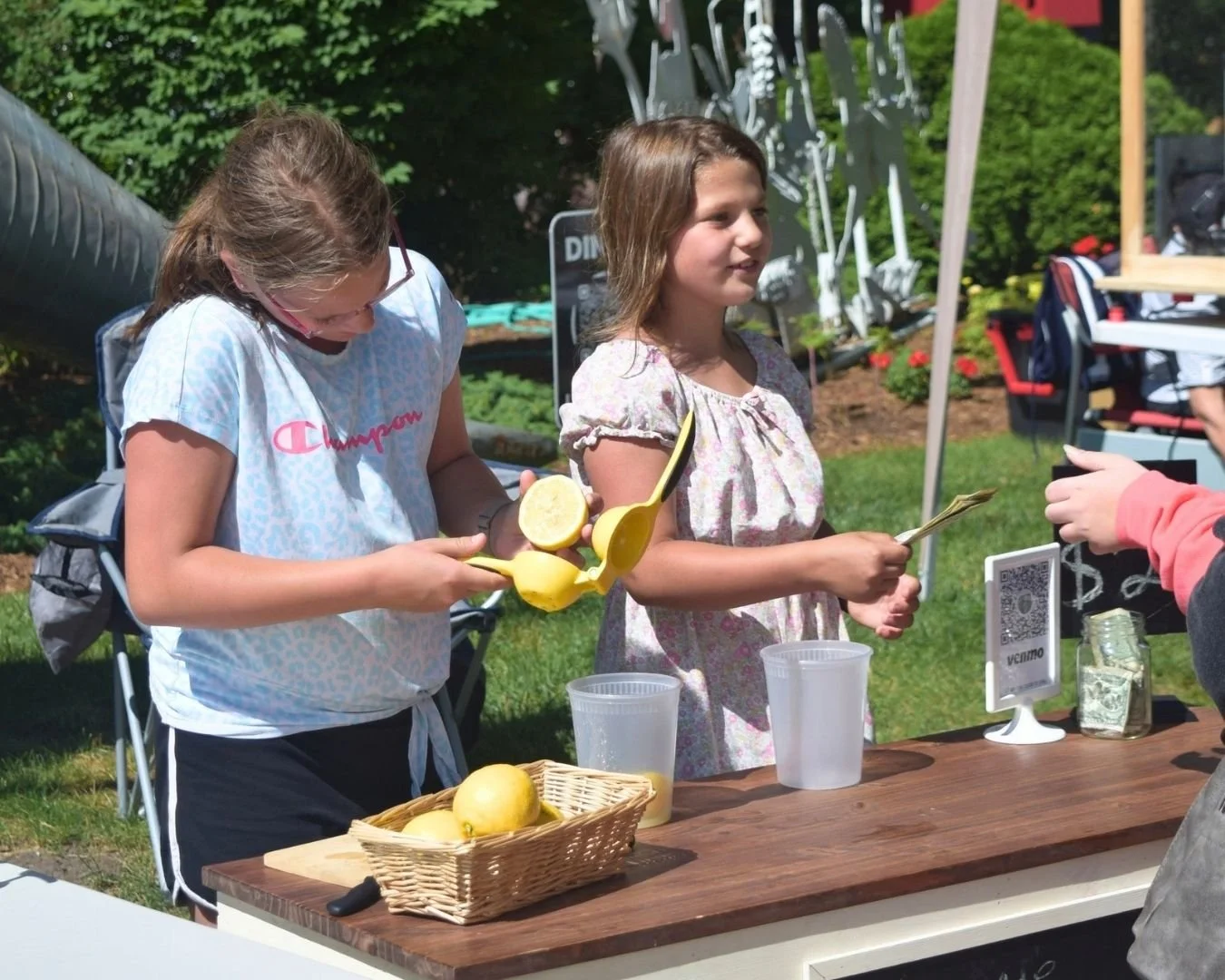 Young entrepreneurs sell fresh lemonade to a customer at the Town Square Summer Market in Green Lake.