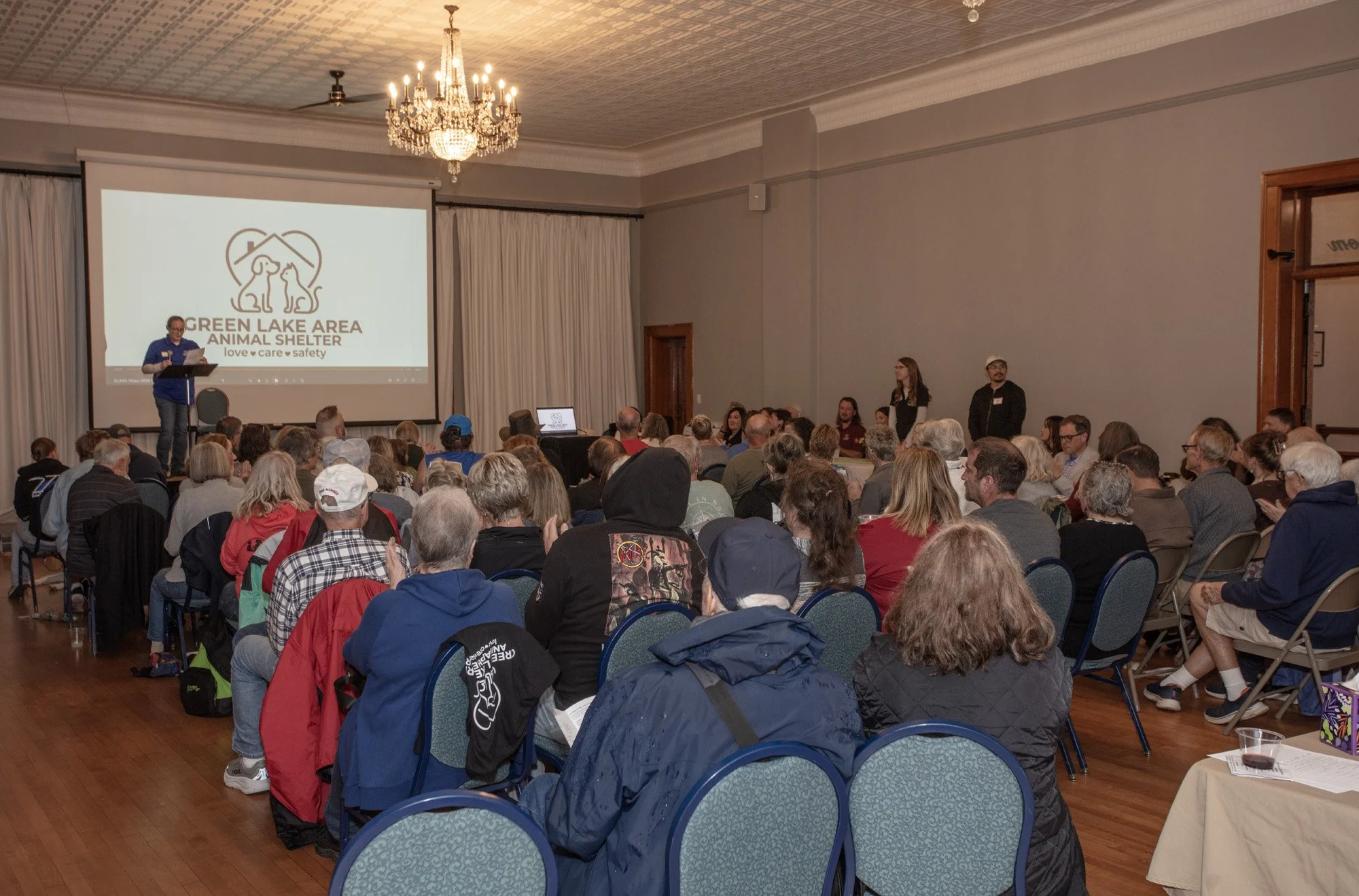 Community members attend a presentation in the Town Square Ballroom, with a speaker at the front of the room.