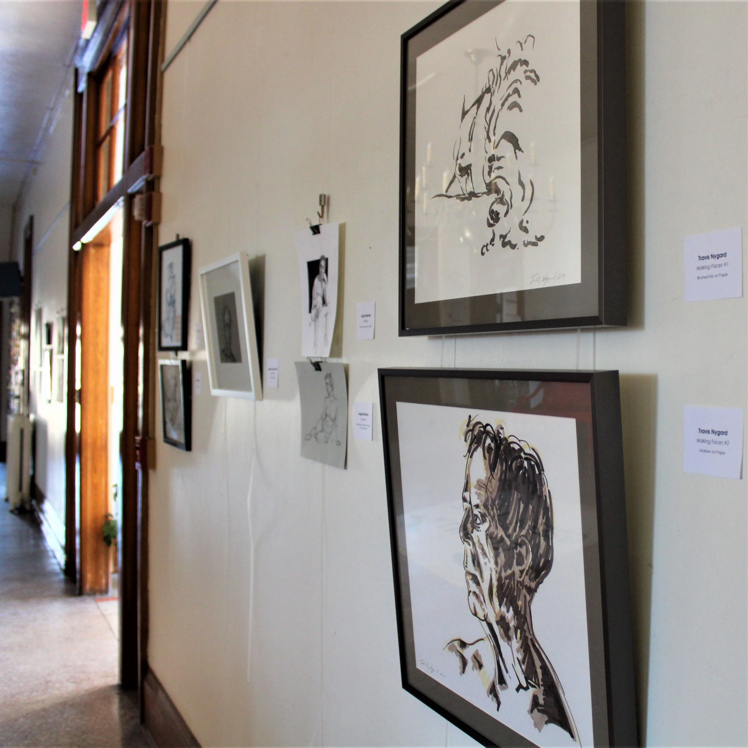 Framed drawings and artwork displayed along the wall of the Town Square Lobby Art Gallery in Green Lake, Wisconsin.
