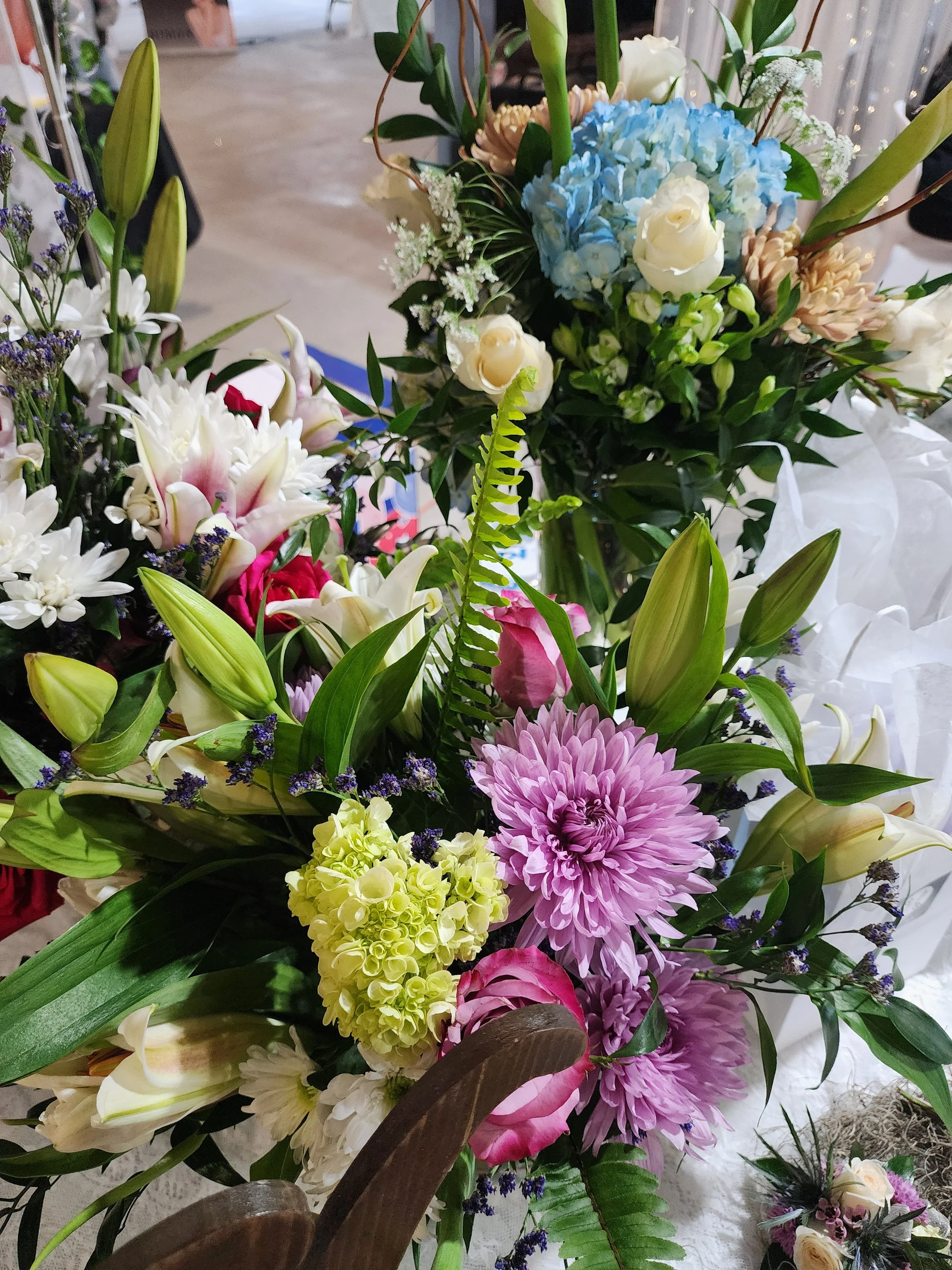 Colorful wedding floral arrangements featuring pink roses, lilies, hydrangeas and purple chrysanthemums displayed at the Wedding & Event Expo.