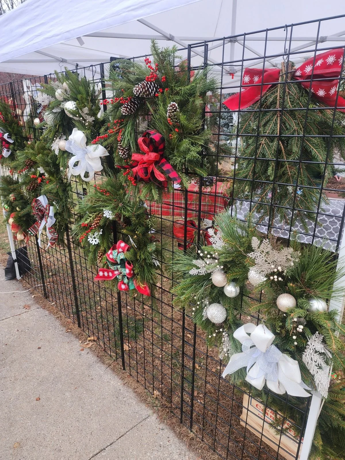 Handmade evergreen holiday wreaths decorated with festive ribbons, pinecones, berries and ornaments at the Holiday Market.