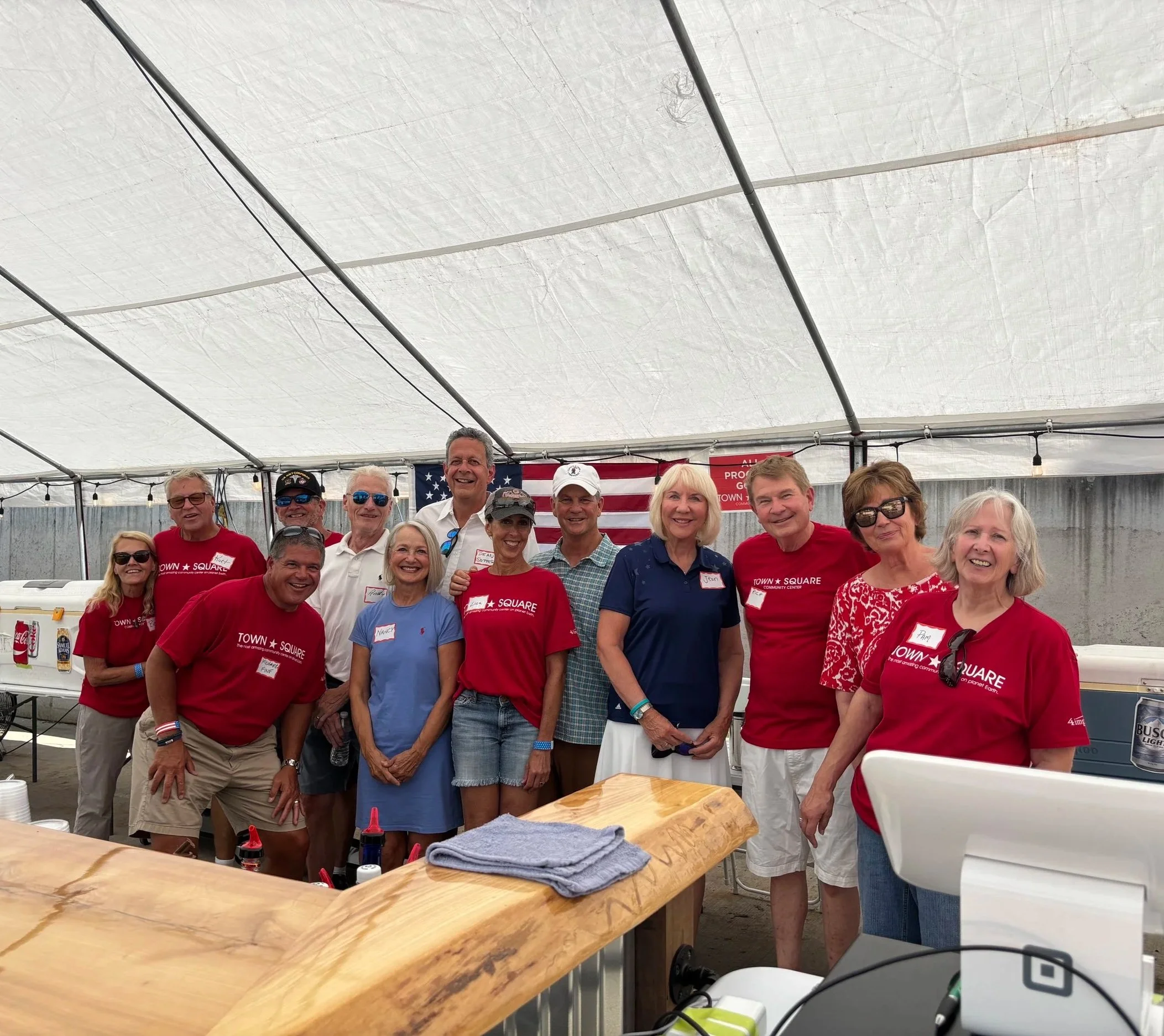 Town Square volunteers and community members pose for a group photo behind the bar during Party on the Pond in Green Lake, Wisconsin.