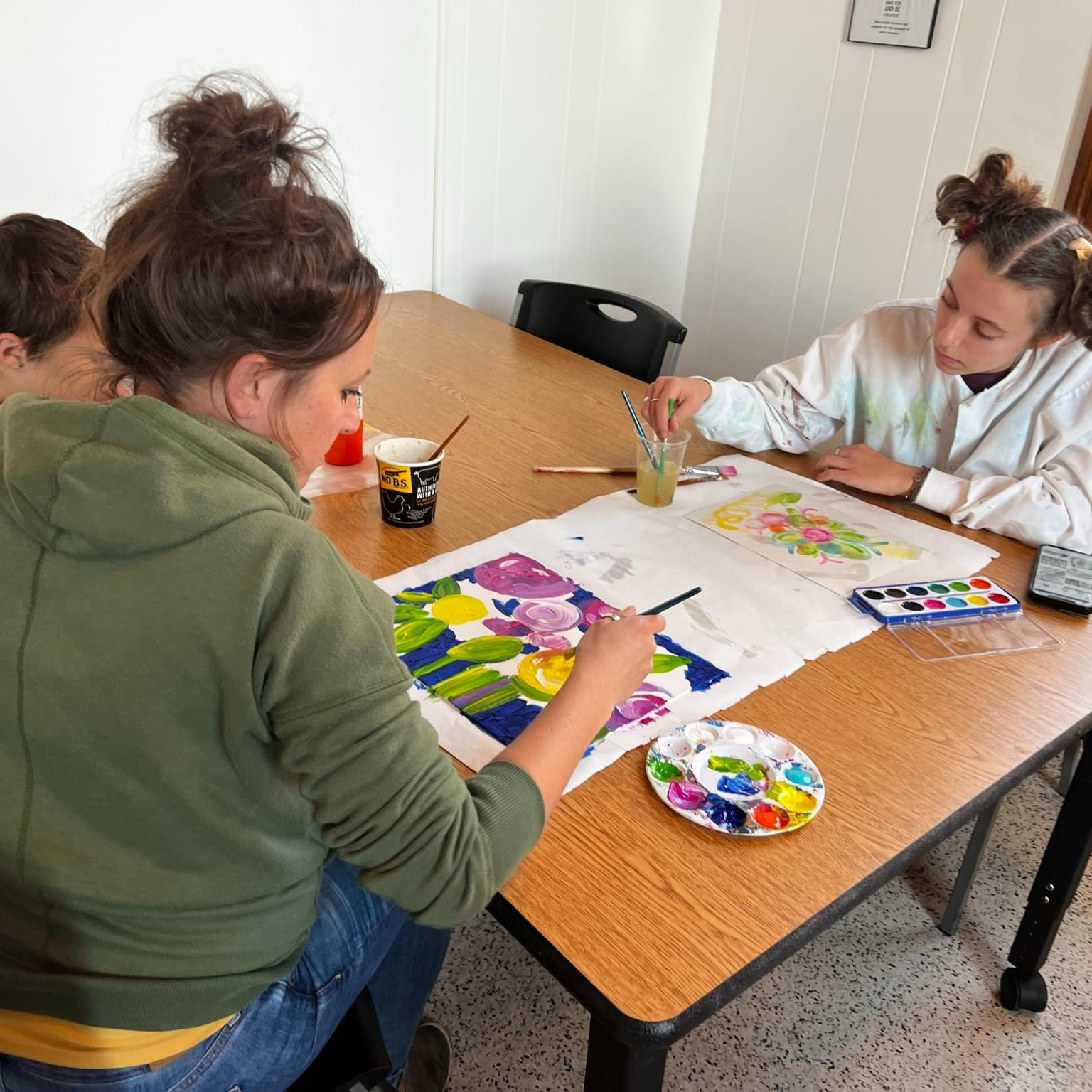 Children and adults painting in the MarkerSpace using acrylic paint and watercolors.
