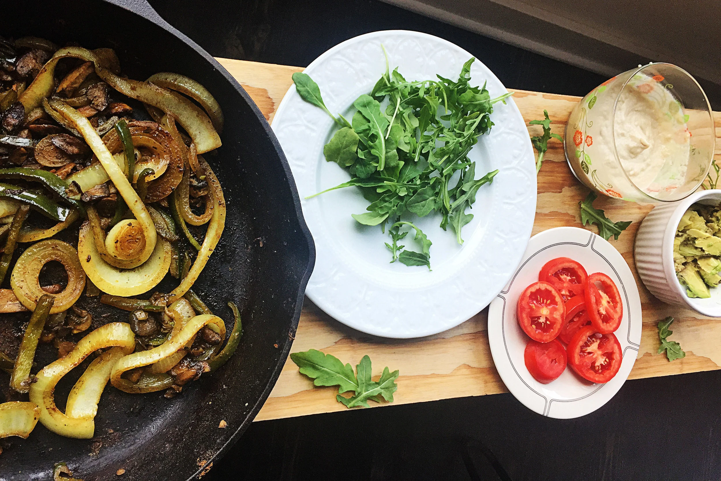 7. The final step is to prep our toppings bar. Whisk together the garlic lime tahini spread, place in a serving bowl. Chop tomatoes and avocado. Grab some arugula. I like to serve mine as a toppings bar since not everyone loves all the ingredients, so they can make their own. 