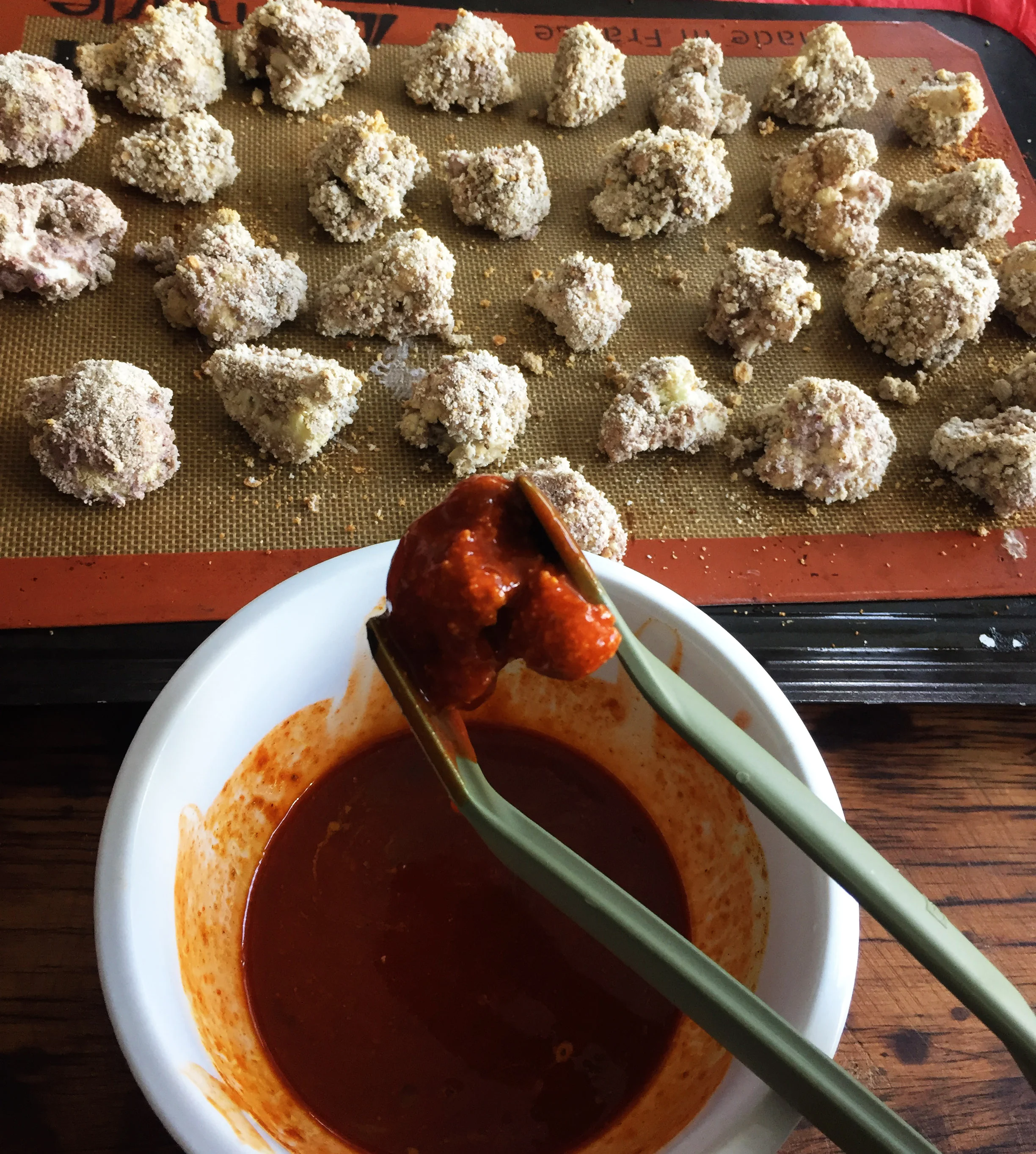 8. After the wings come out of the oven, using tongs, dip into the sauce, shake it off, and place back on the pan.